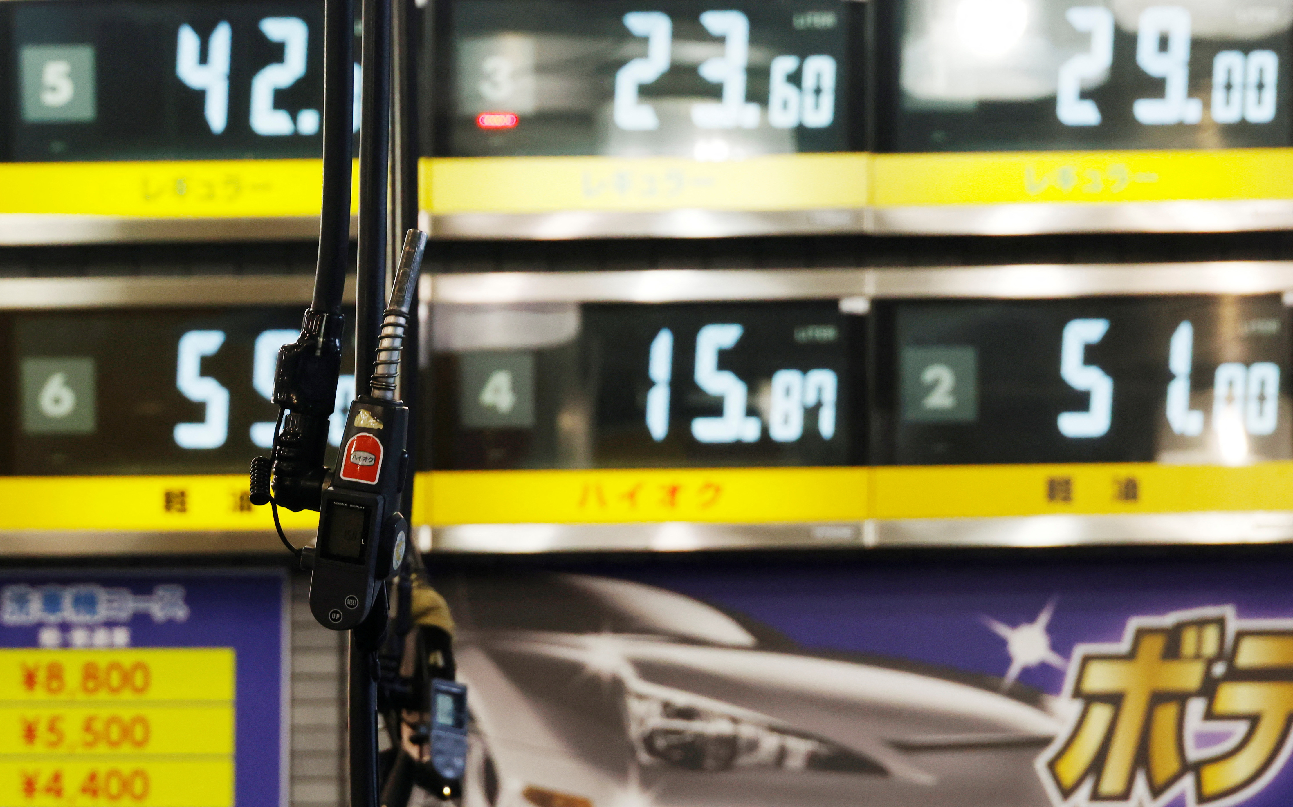 Gasoline fuel guns are pictured in front of fuel boards at a gasoline station in Tokyo