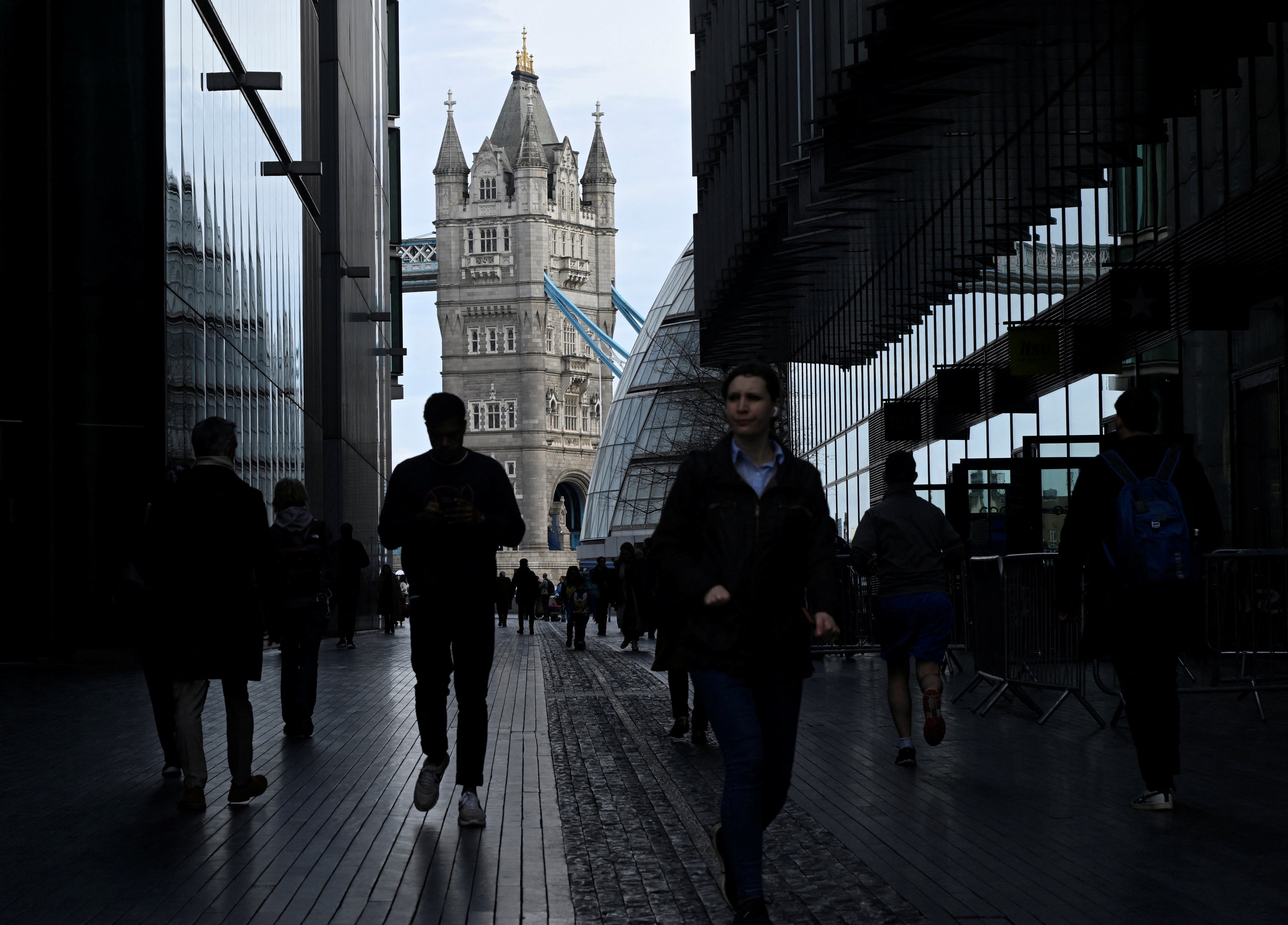 People walk through the 'More London' business district with Tower Bridge seen behind in London