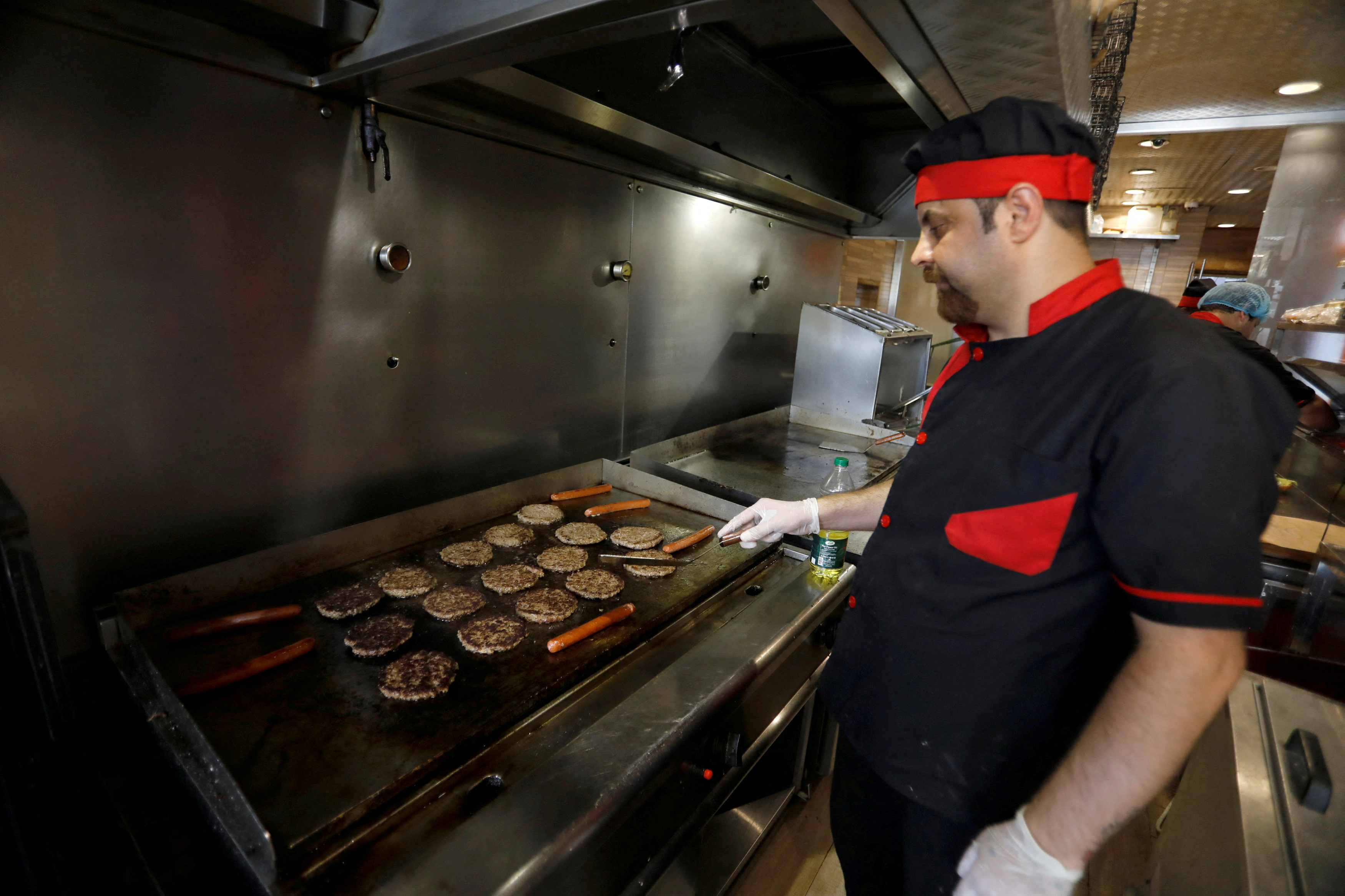 A man cooks burgers on the grill inside a restaurant in Baghdad