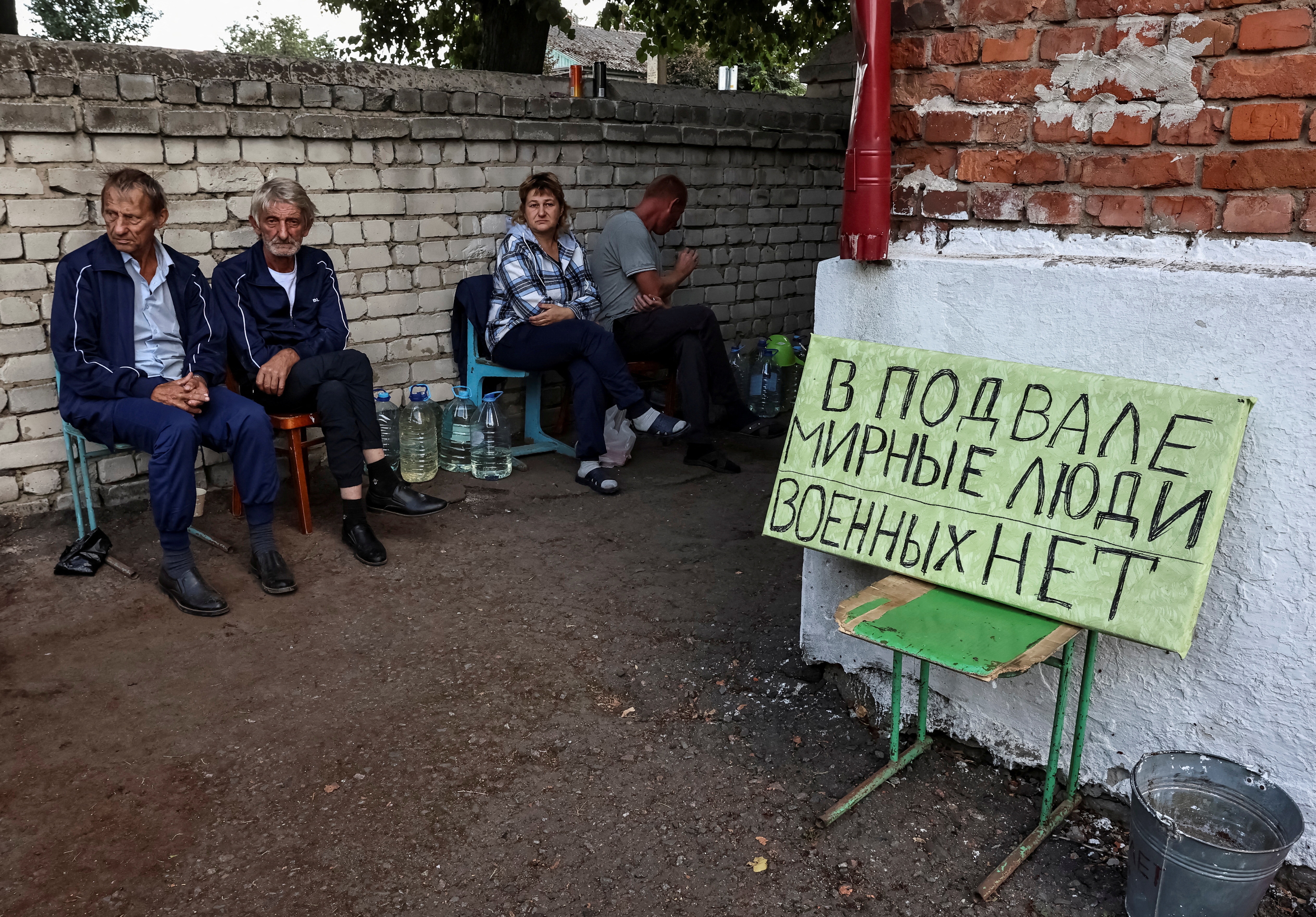 Russian local residents sit near a shelter where they were hiding during recent fighting between Ukrainian and Russian forces in the town of Sudzha