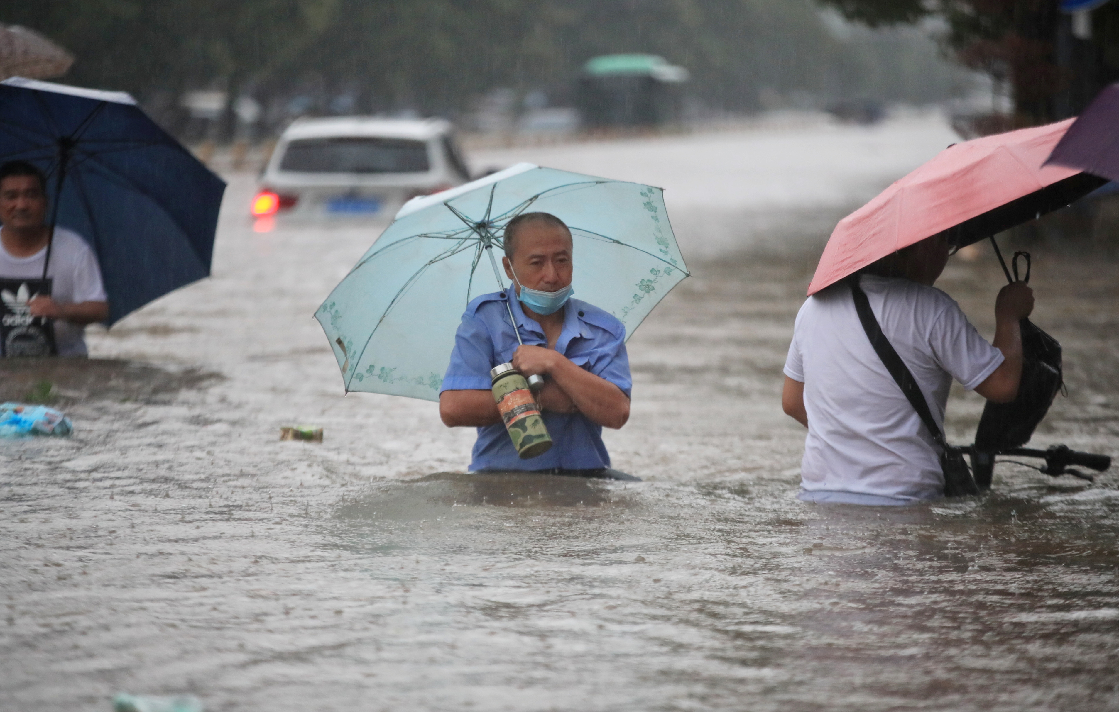 Residents wade through floodwaters on a flooded road amid heavy rainfall in Zhengzhou, Henan province, China July 20, 2021. Picture taken July 20, 2021. China Daily via REUTERS ATTENTION EDITORS - THIS IMAGE WAS PROVIDED BY A THIRD PARTY. CHINA OUT.
