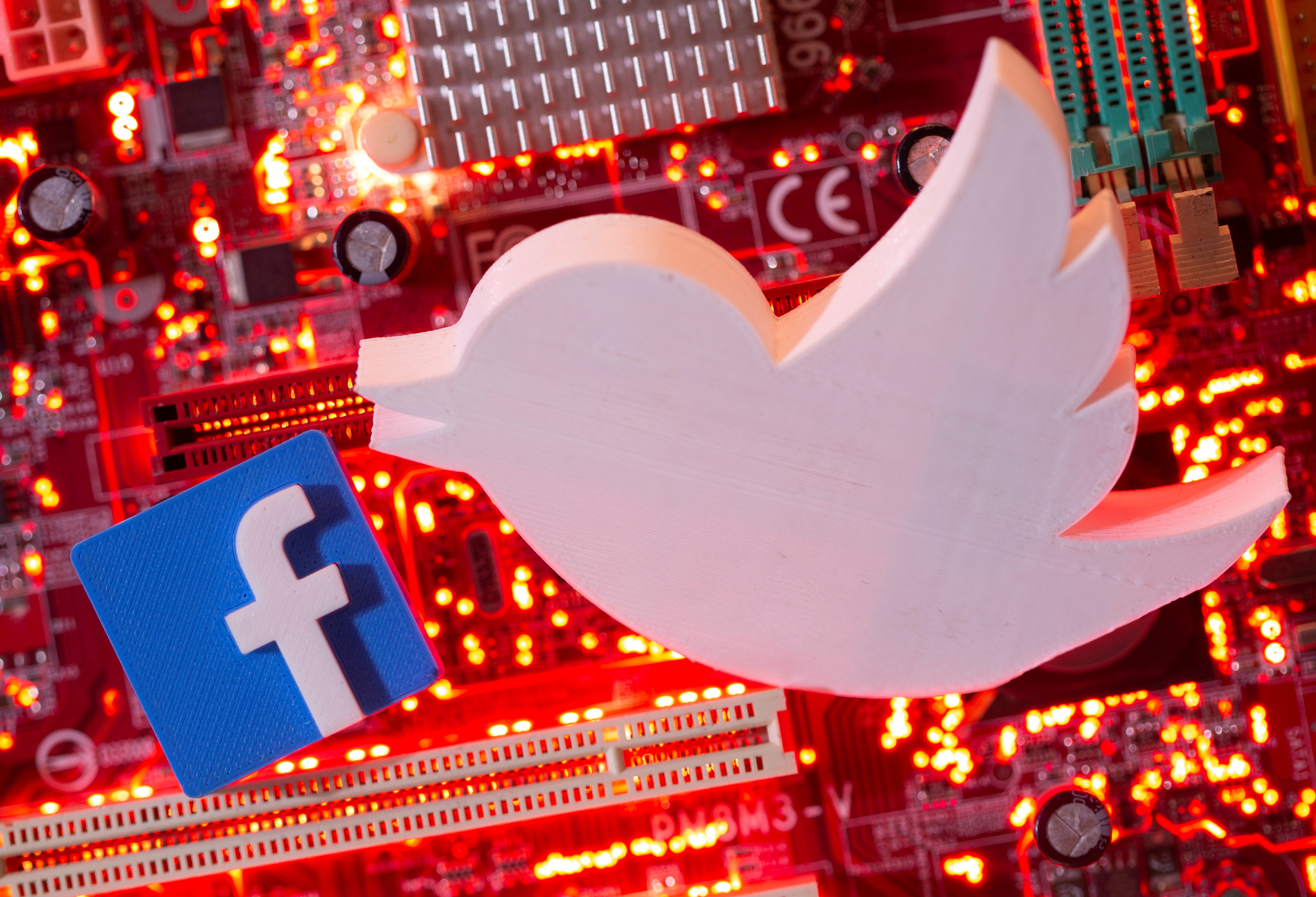 Illustration of 3D printed Facebook and Twitter logos on a computer motherboard