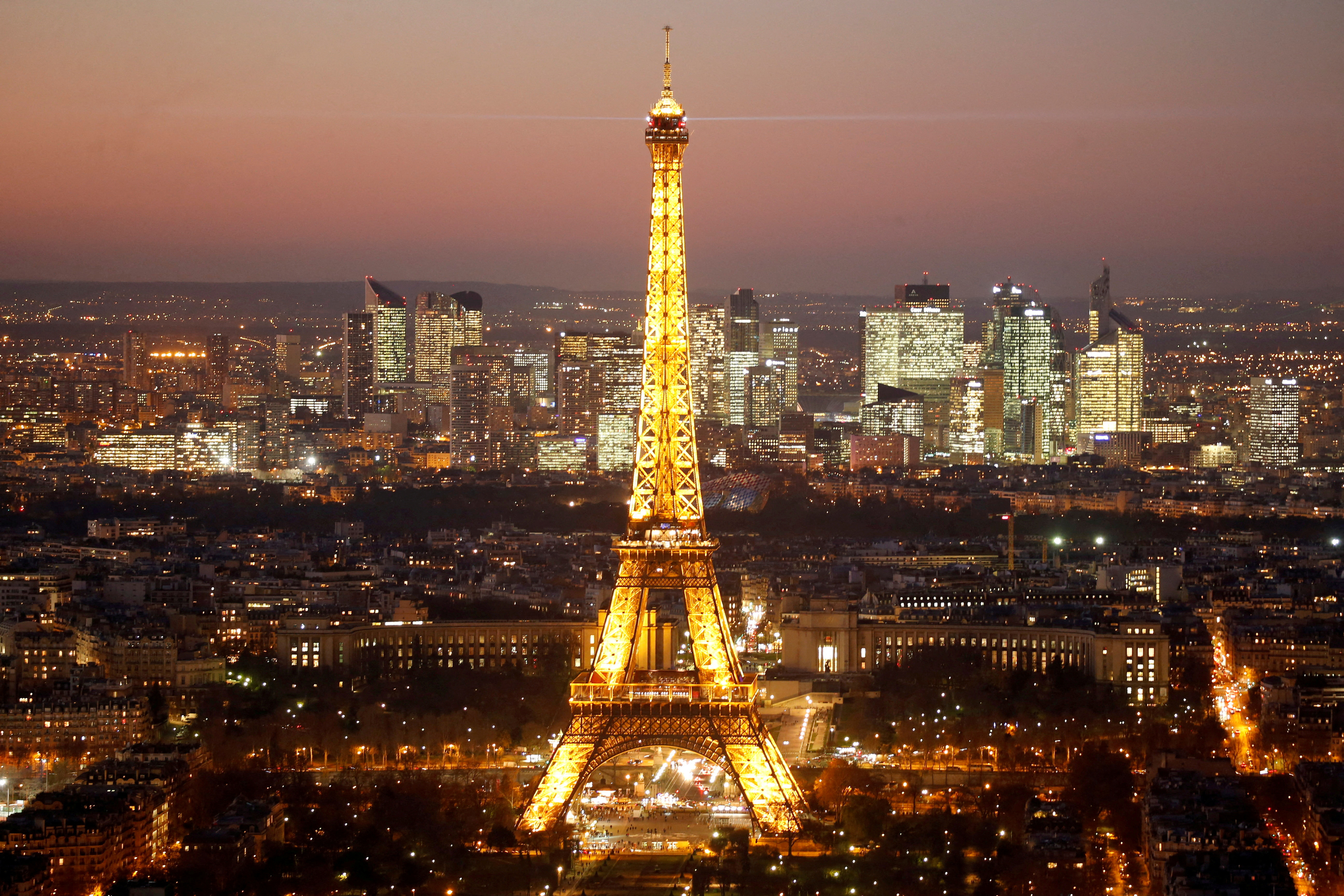 A general view show the illuminated Eiffel Tower and the skyline of La Defense business district at night in Paris