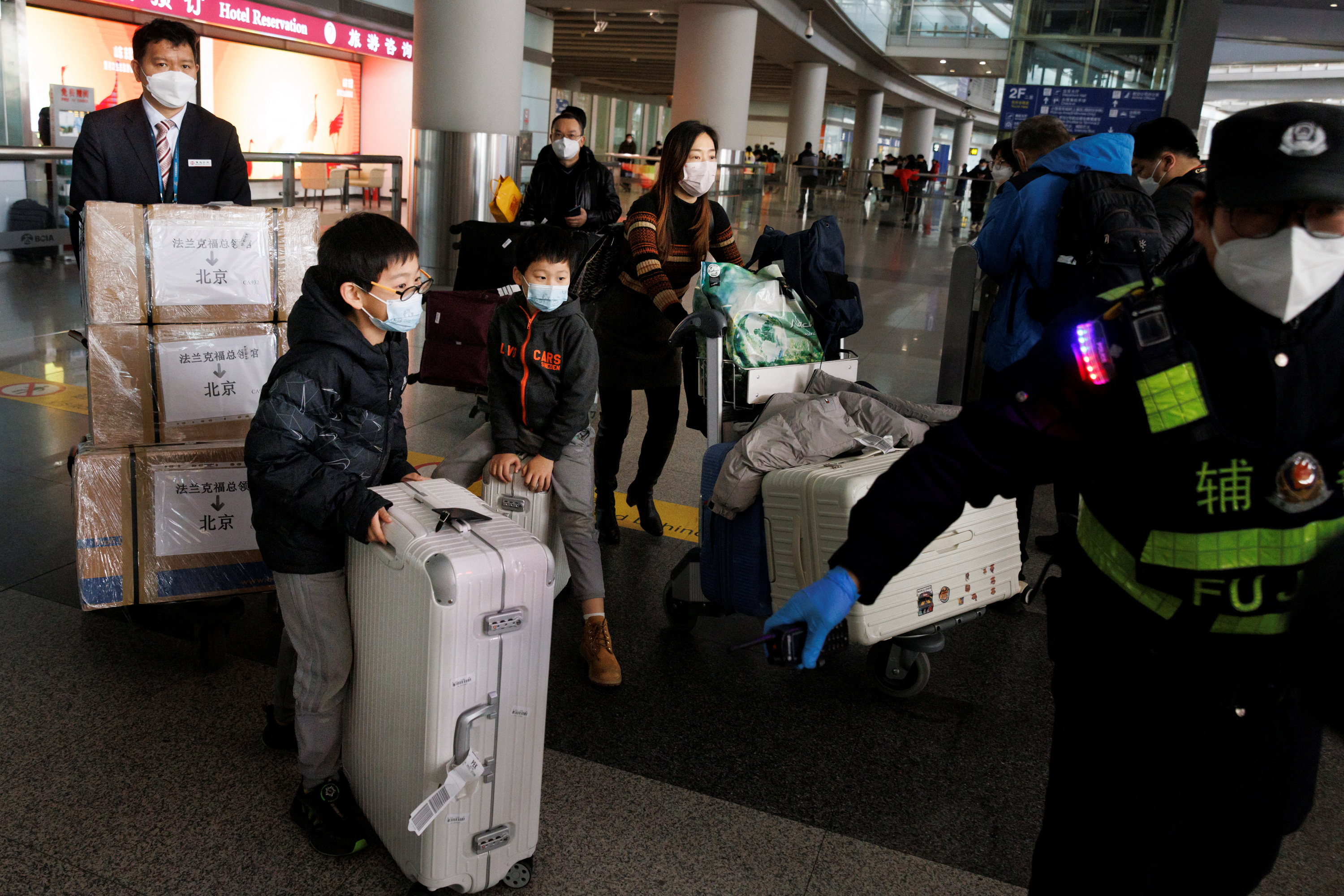 Passengers push their luggage through the international arrivals hall at Beijing Capital International Airport after China lifted the COVID-19 quarantine requirement for inbound travellers in Beijing
