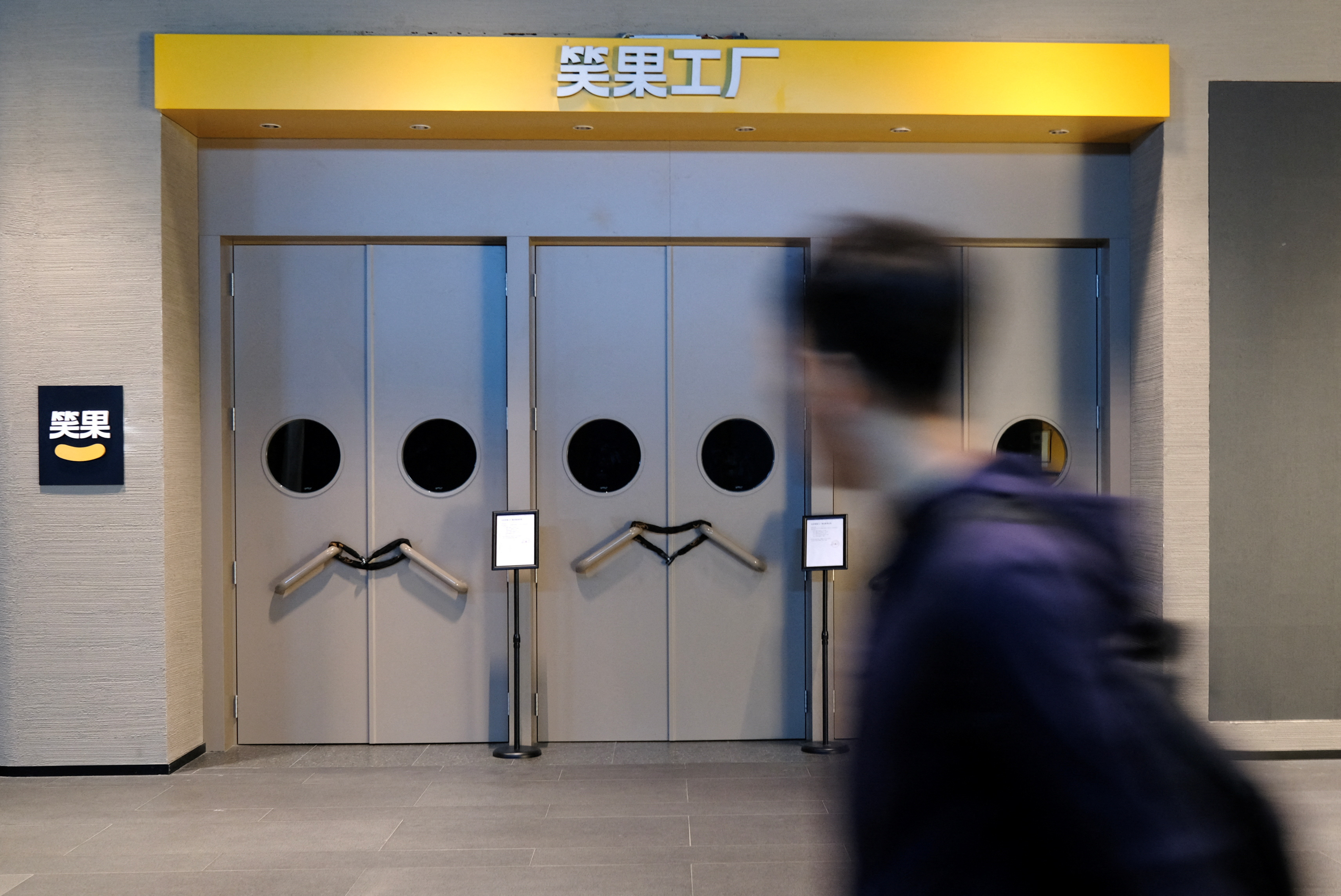 A person walks past a show venue of stand-up comedy company Xiaoguo Culture Media Co that has closed its business with a notice of show cancellation, in Beijing