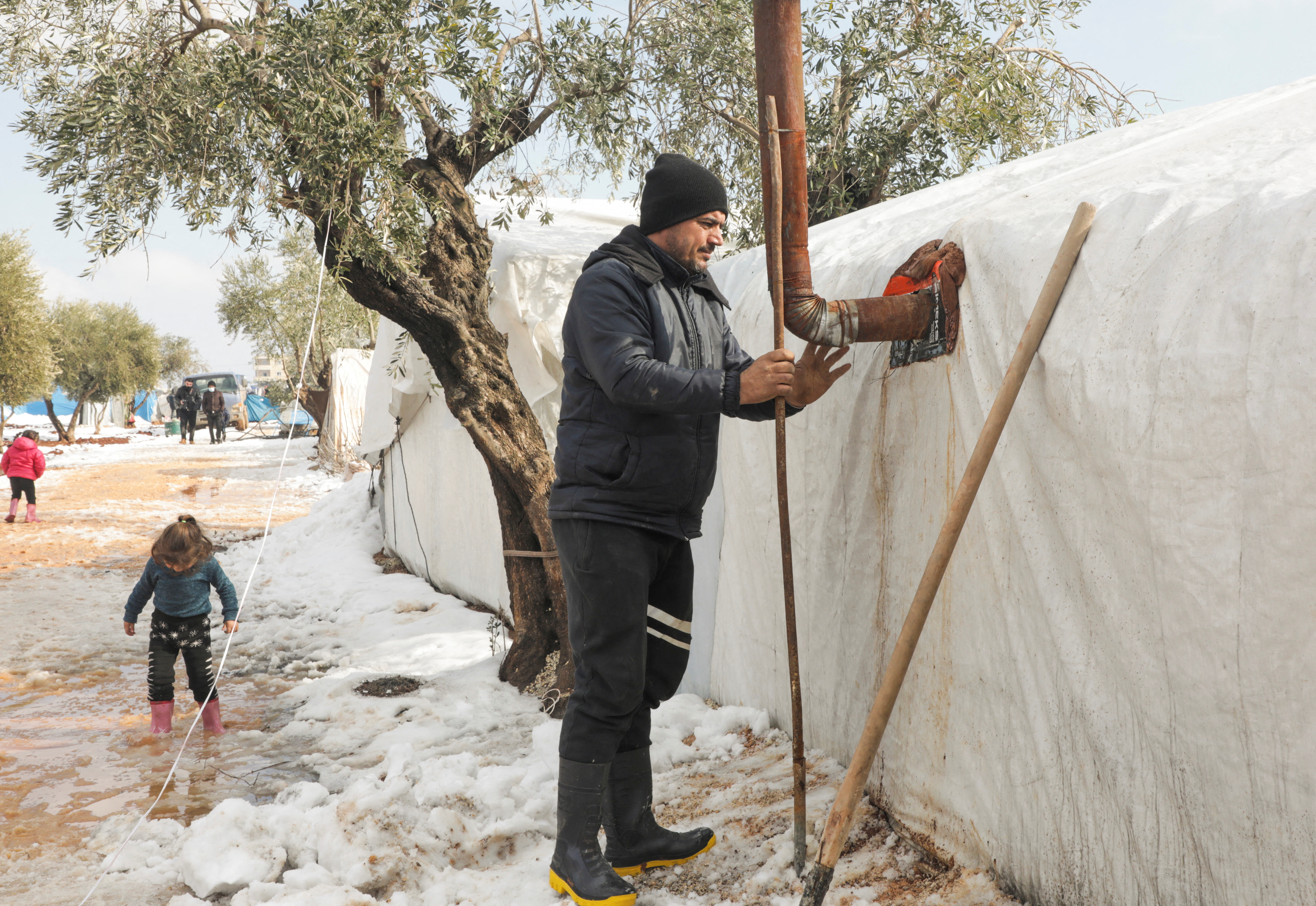 Bilal Ibrahim al-Sayyar, an internally displaced man clears snow from his tent at a camp in the Aleppo countryside
