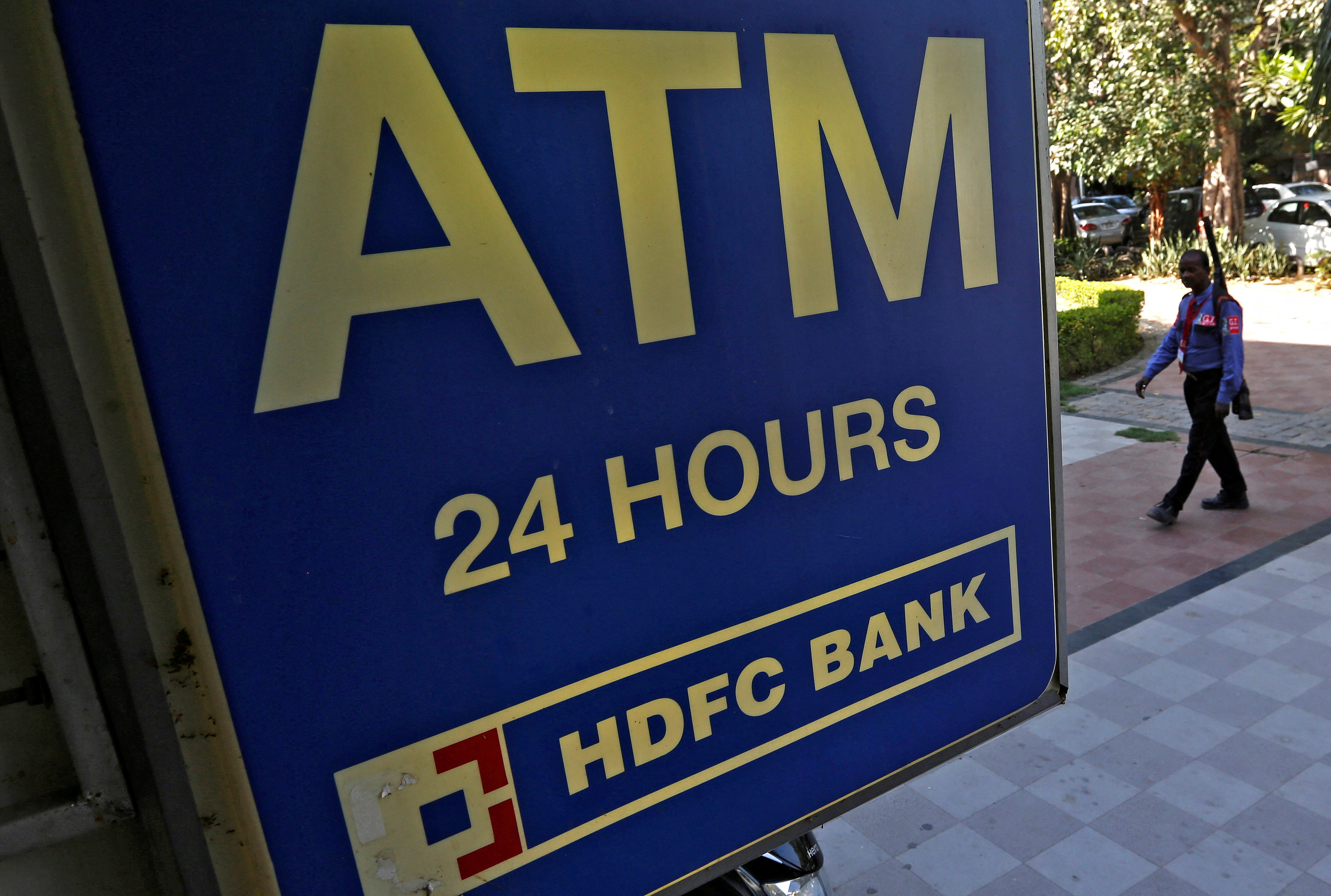 A private security guard moves past a signboard of a HDFC Bank ATM in New Delhi