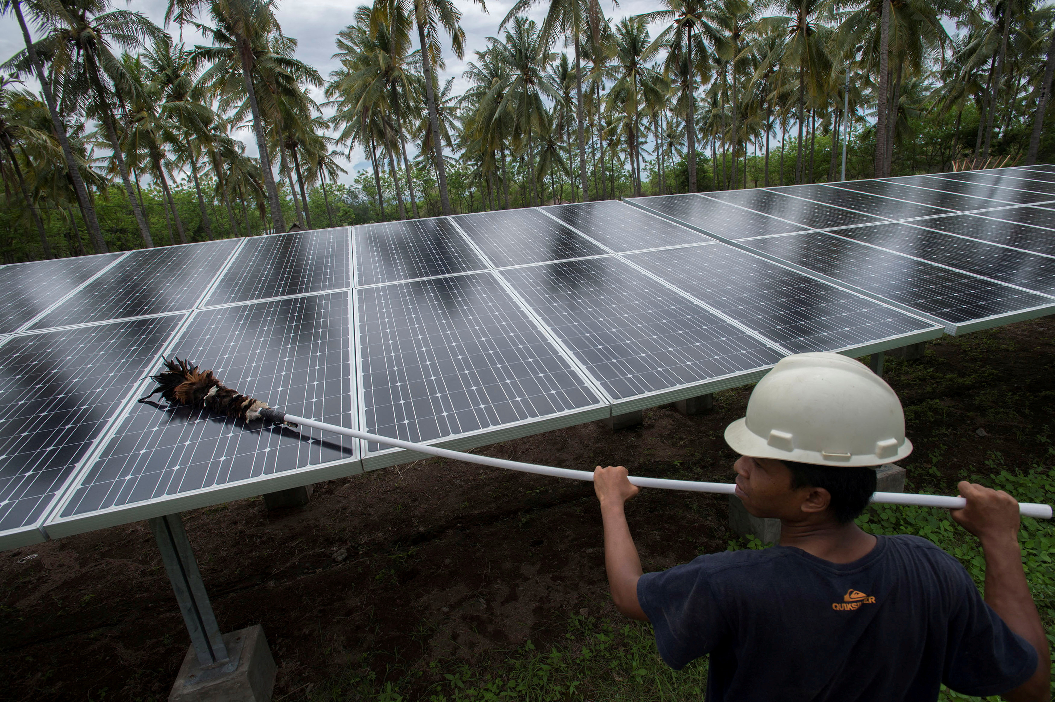 An employee of PT Perusahaan Listrik Negara (PLN) cleans the surface of solar panels at a solar power generation plant in Gili Meno island