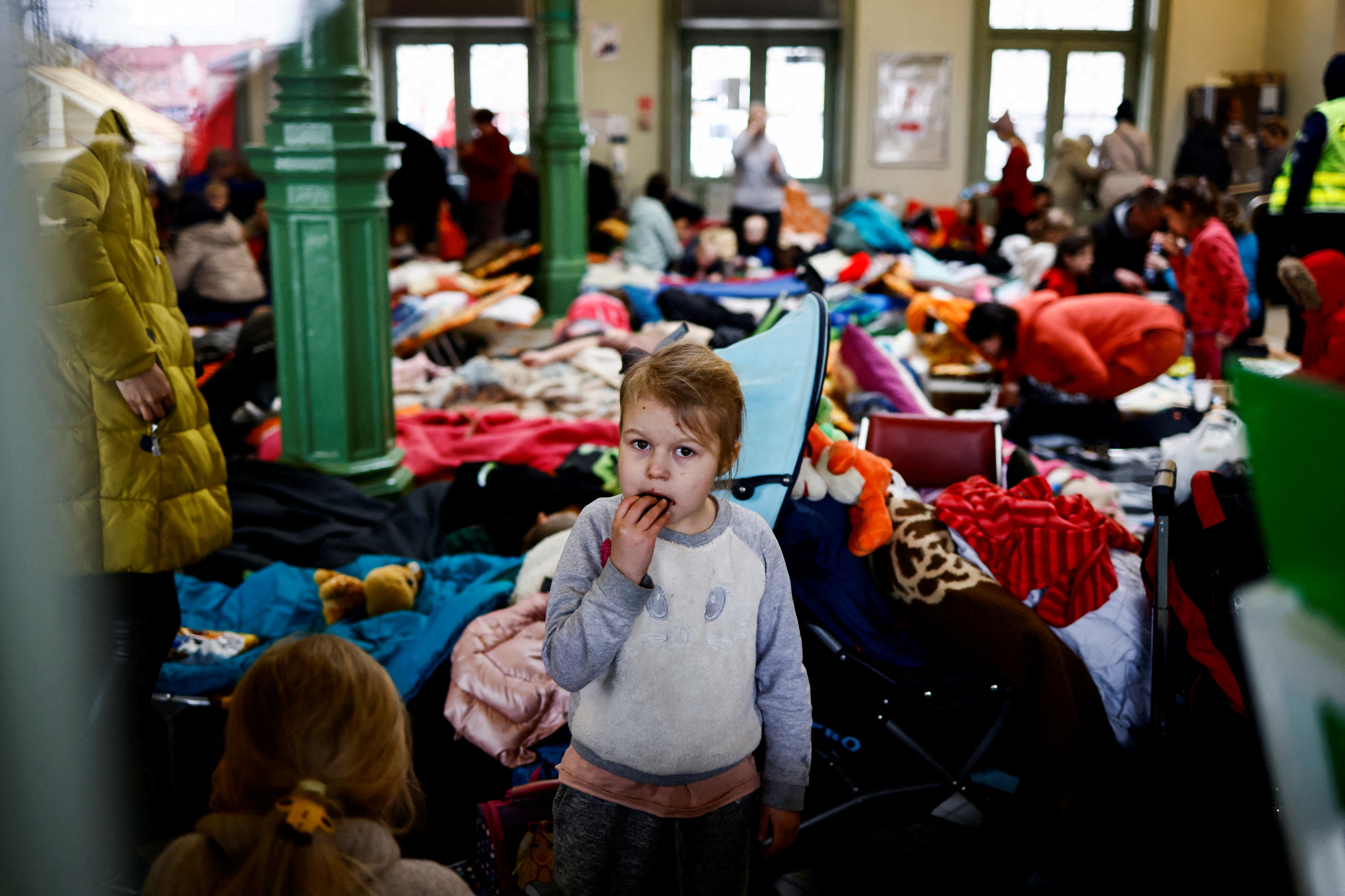 A child eats a cookie as she stands in a temporary accommodation for refugees at the train station, after fleeing Russian invasion of Ukraine, in Przemysl