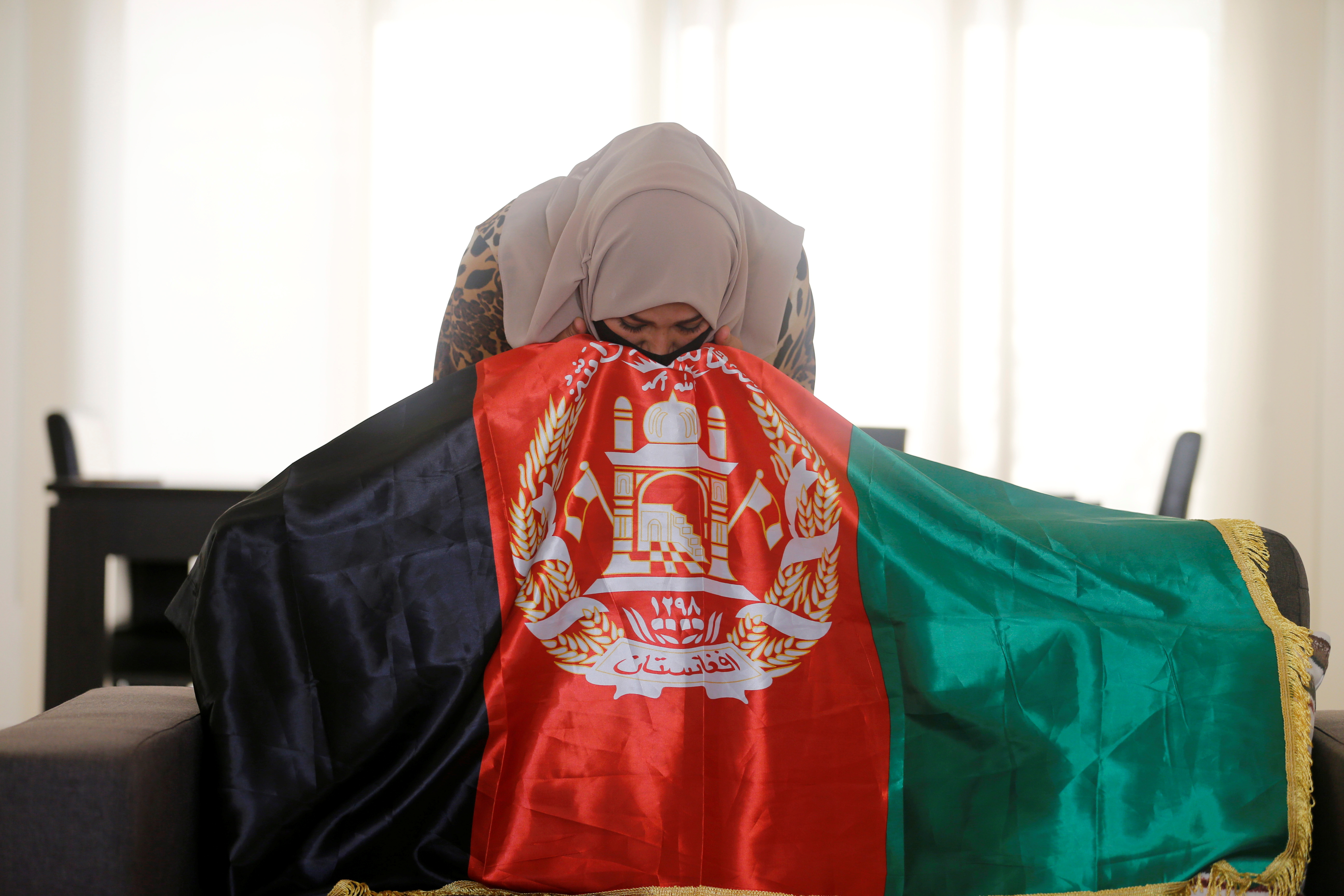 Mariam Sayar, an Afghani evacuee kisses her national flag before speaking to Reuters at a temporary residence compound in Doha, Qatar