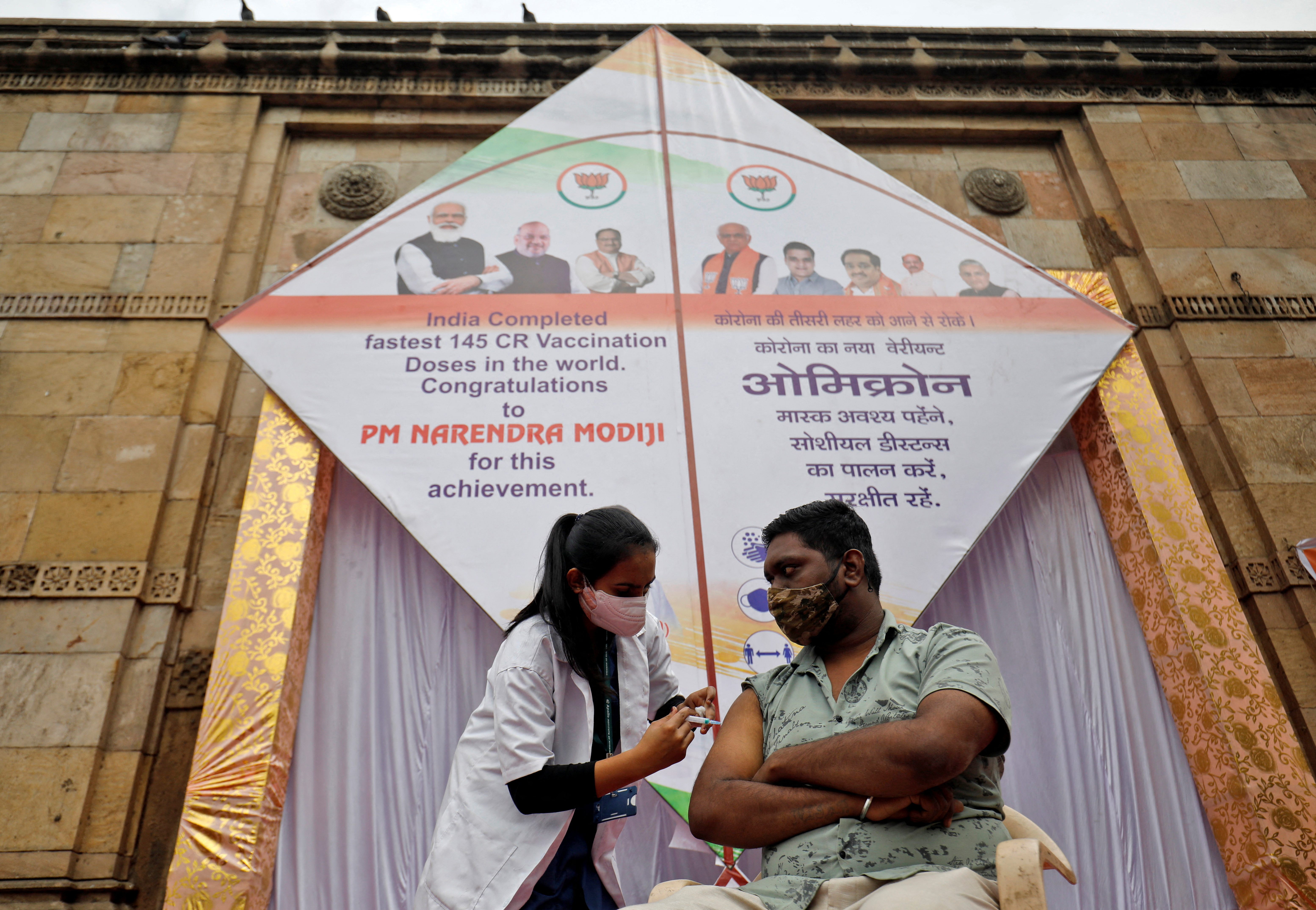 A man receives a dose of vaccine against the coronavirus disease (COVID-19) in front of a giant kite in Ahmedabad