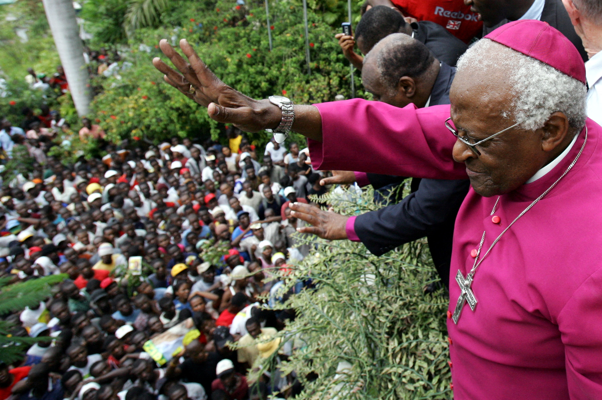 South African Nobel Peace Prize laureate Desmond Tutu tries to calm thousand of supporters of Haitian presidential candidate Rene Preval, as they try to get into the Montana Hotel, where the Provisional Electoral Center cancelled a press conference to announce polling results yesterday, in Port-au-Prince, February 13, 2006.  REUTERS/Carlos Barria/File Photo