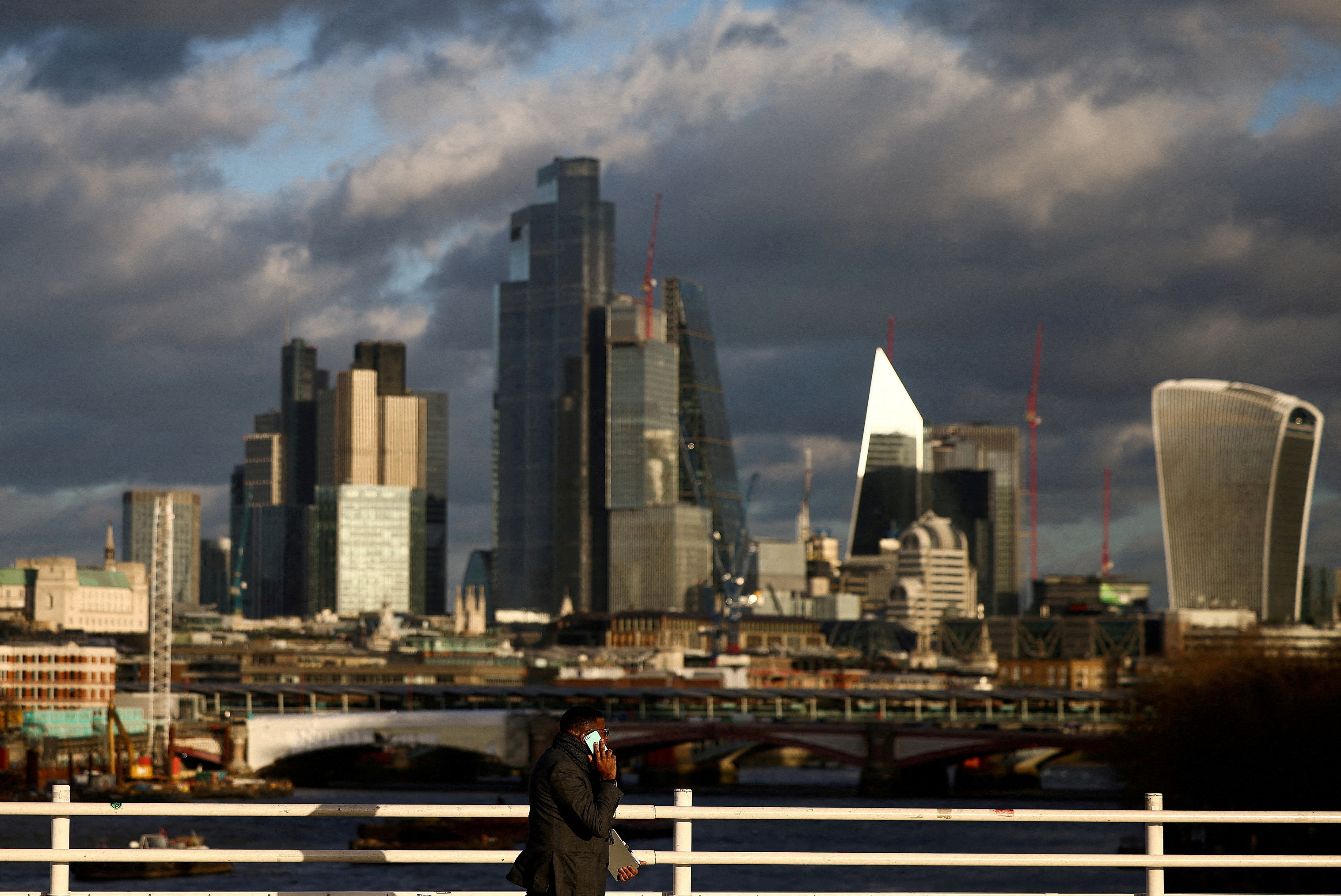 kFILE PHOTO: A person walks across Waterloo Bridge with the City of London financial district in the background, in London