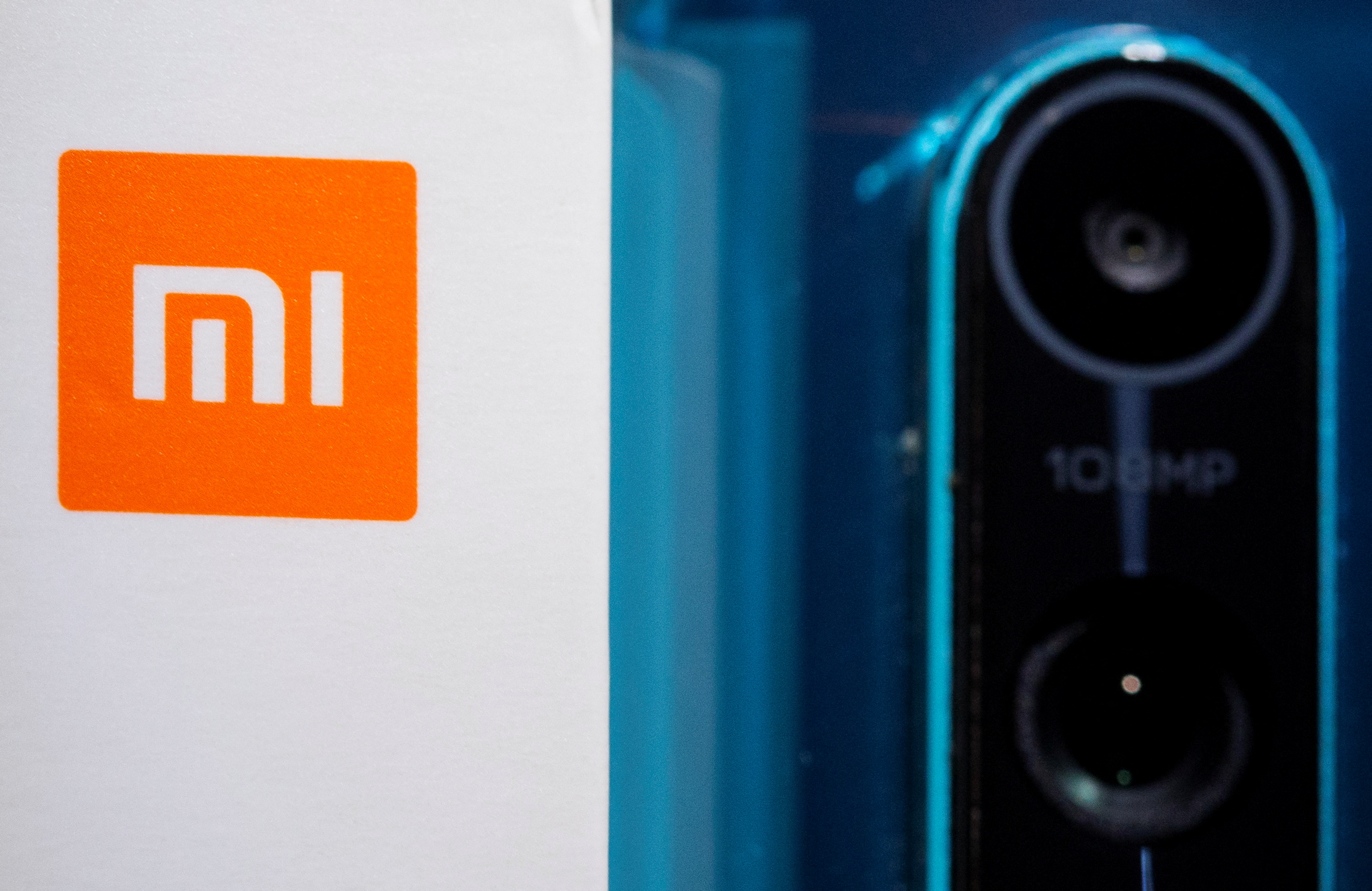 Xiaomi logo is seen next to a smartphone of the same brand in this illustration