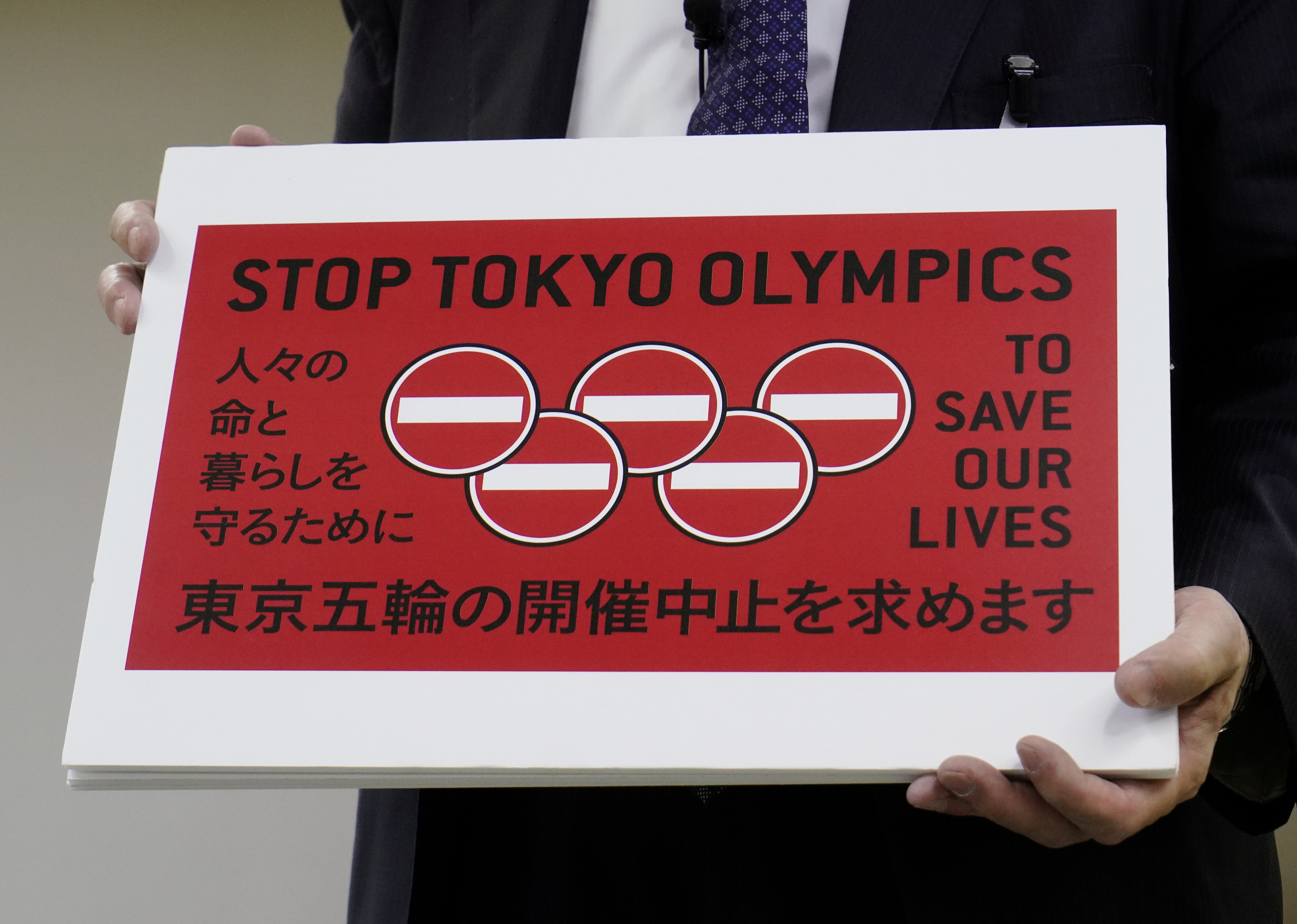Lawyer Kenji Utsunomiya shows off a placard during a news conference after he and anti-Olympics petition organizer to submit a petition calling for the Tokyo 2020 Olympics to be cancelled in Tokyo