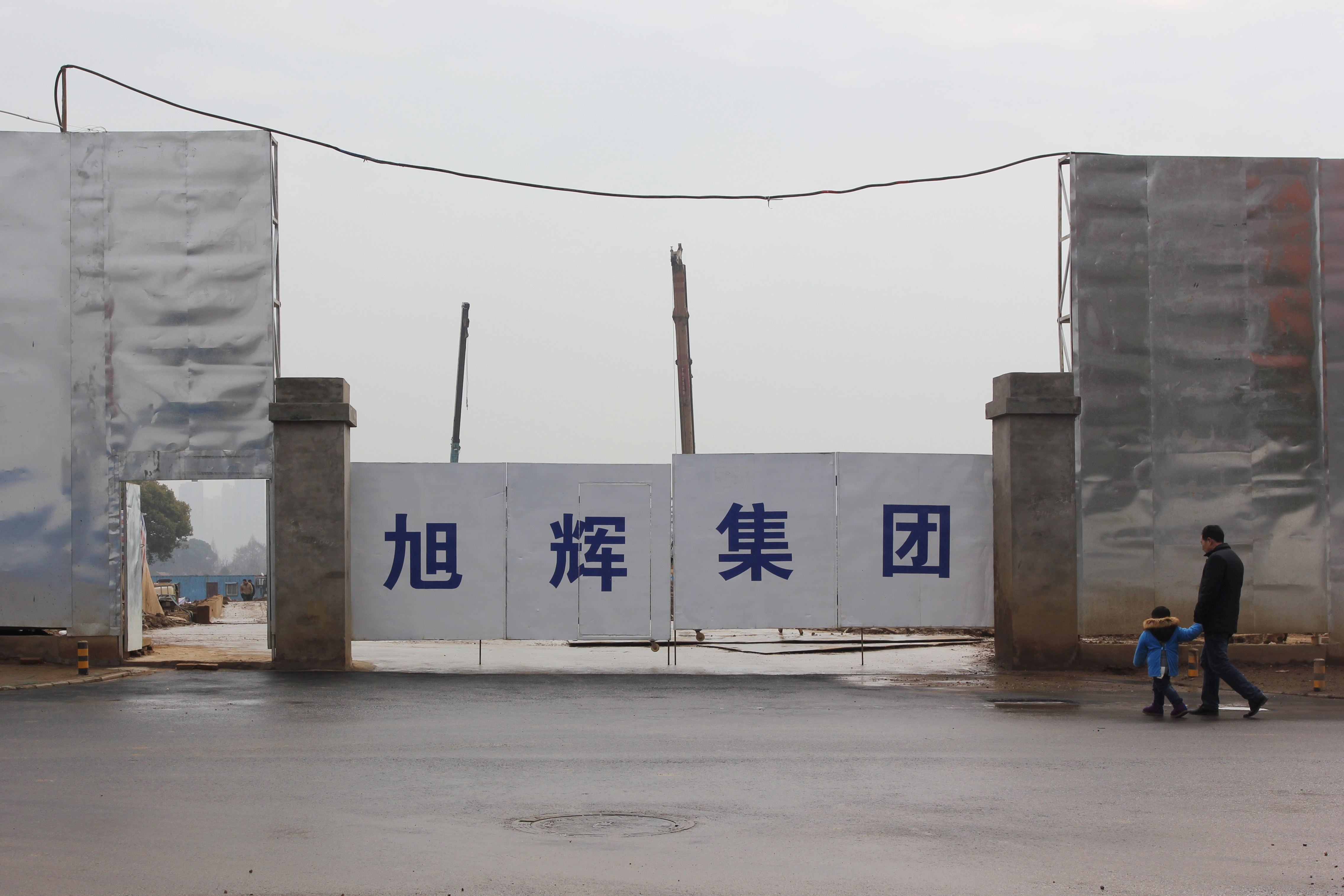 Man and a child walk by a construction site under property developer CIFI Holdings in Wuhan