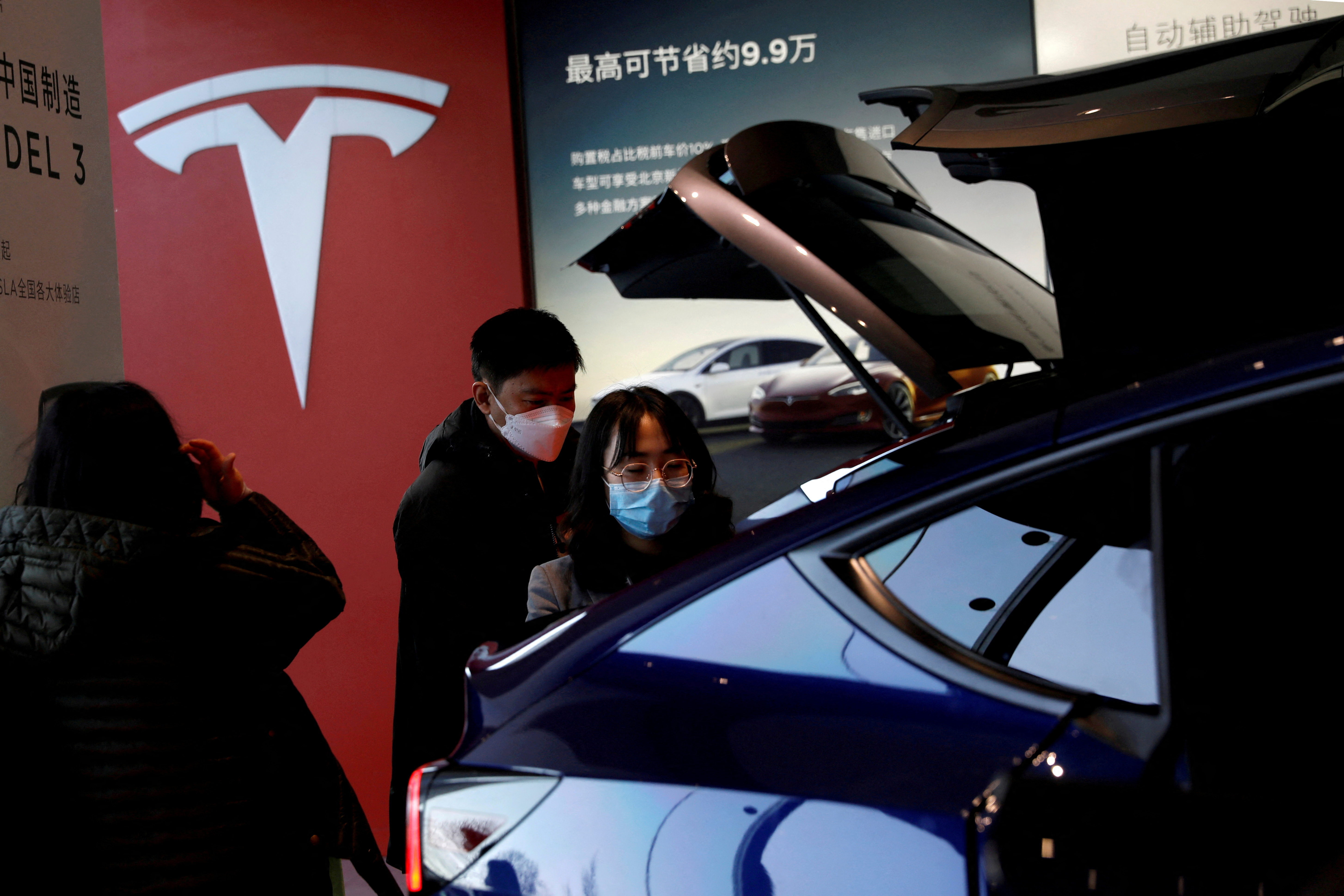 Des visiteurs portant des masques faciaux vérifient un véhicule utilitaire sport (SUV) Tesla Model Y fabriqué en Chine dans la salle d’exposition du constructeur de véhicules électriques à Pékin