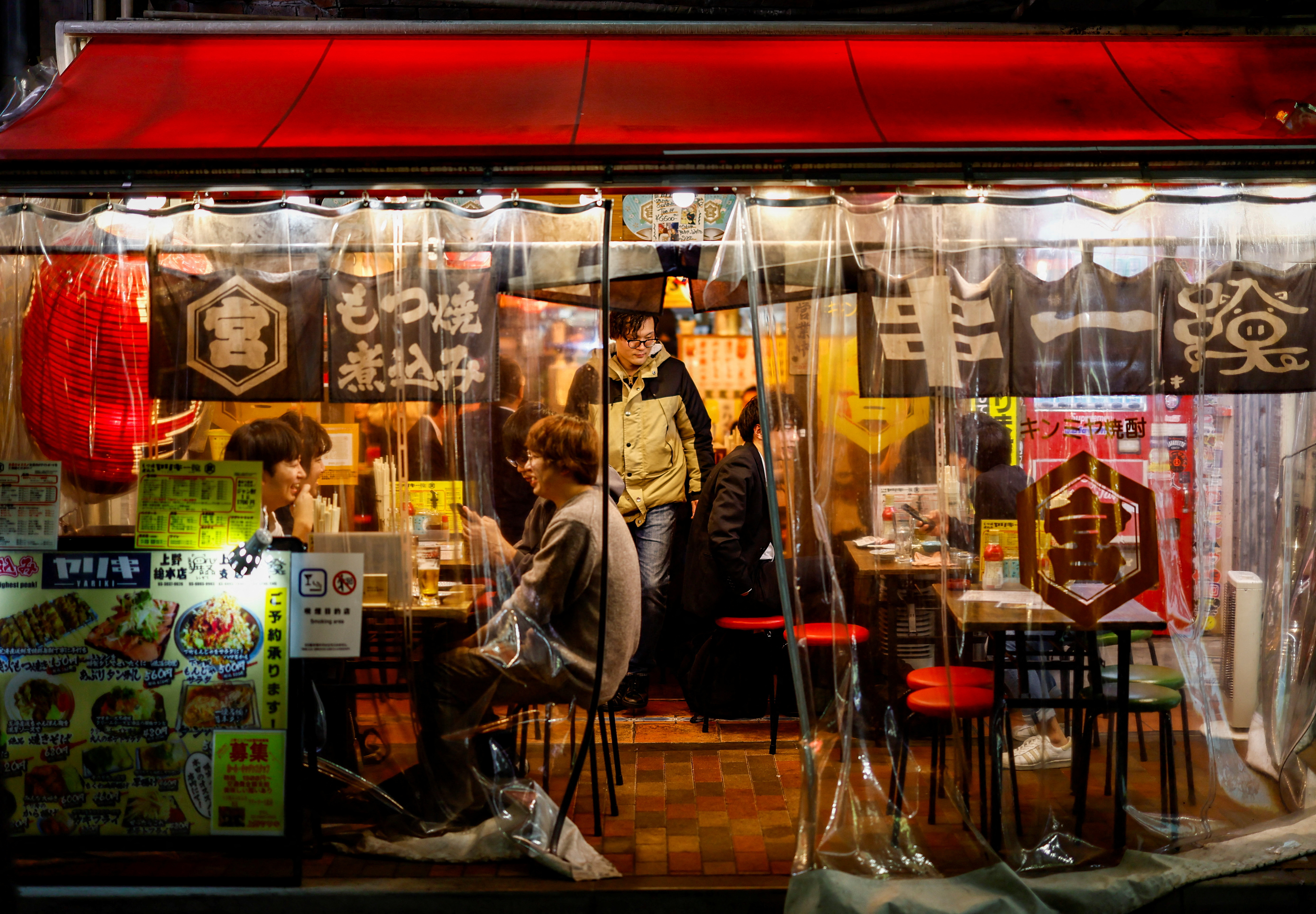 People enjoy drinks and food at an izakaya pub restaurant at the Ameyoko shopping district, in Tokyo