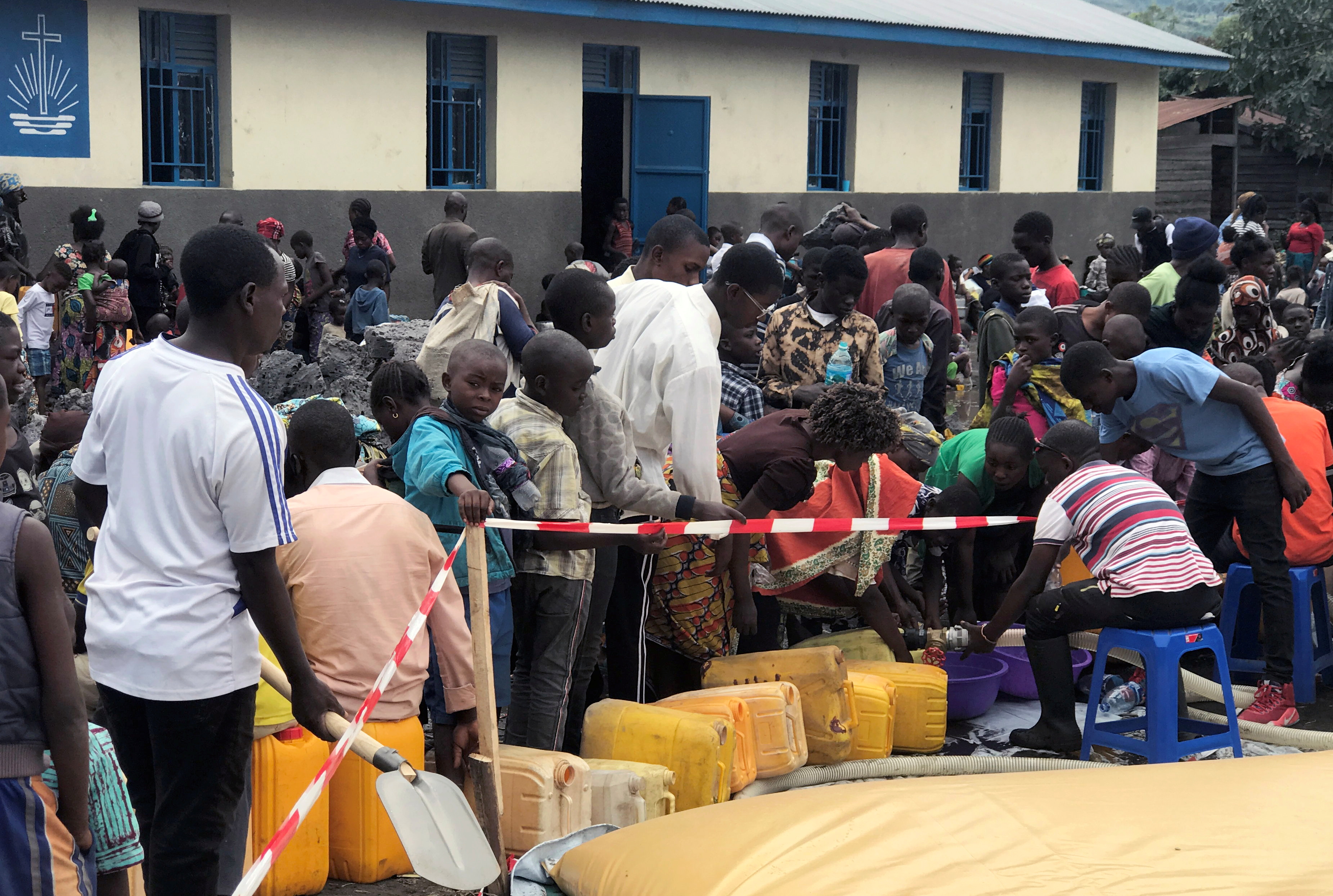 Internally displaced Congolese people who fled from recurrent earth tremors after the volcanic eruption of Mount Nyiragongo, collect water outside a church in Sake town, near Goma