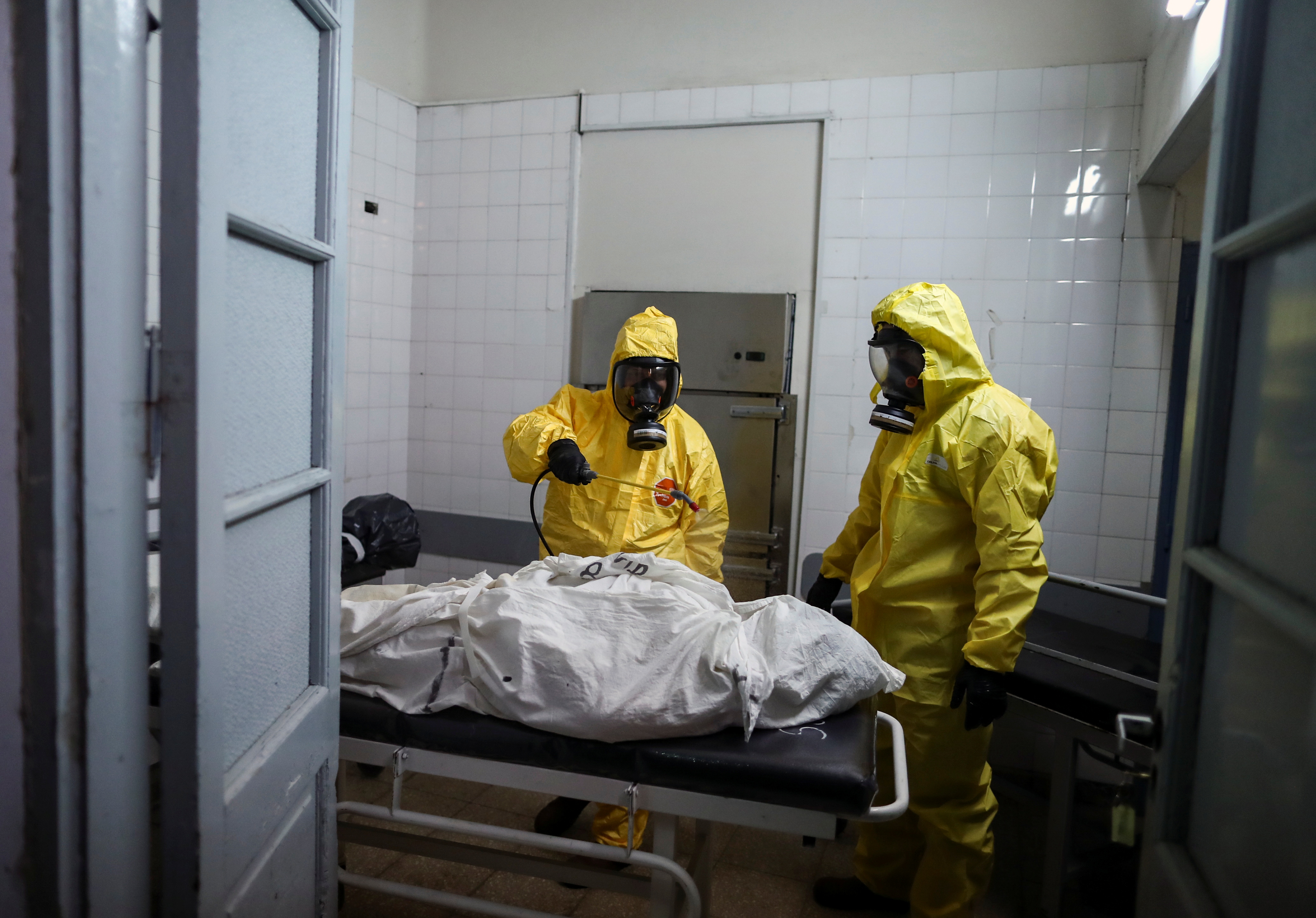 Gaston Rusichi and Oscar Oliva, members of the Department of High Risk Units (DUAR), disinfect a body of a person who died from the coronavirus disease (COVID-19) in a morgue, in Cordoba, Argentina, July 11, 2021. REUTERS/Agustin Marcarian