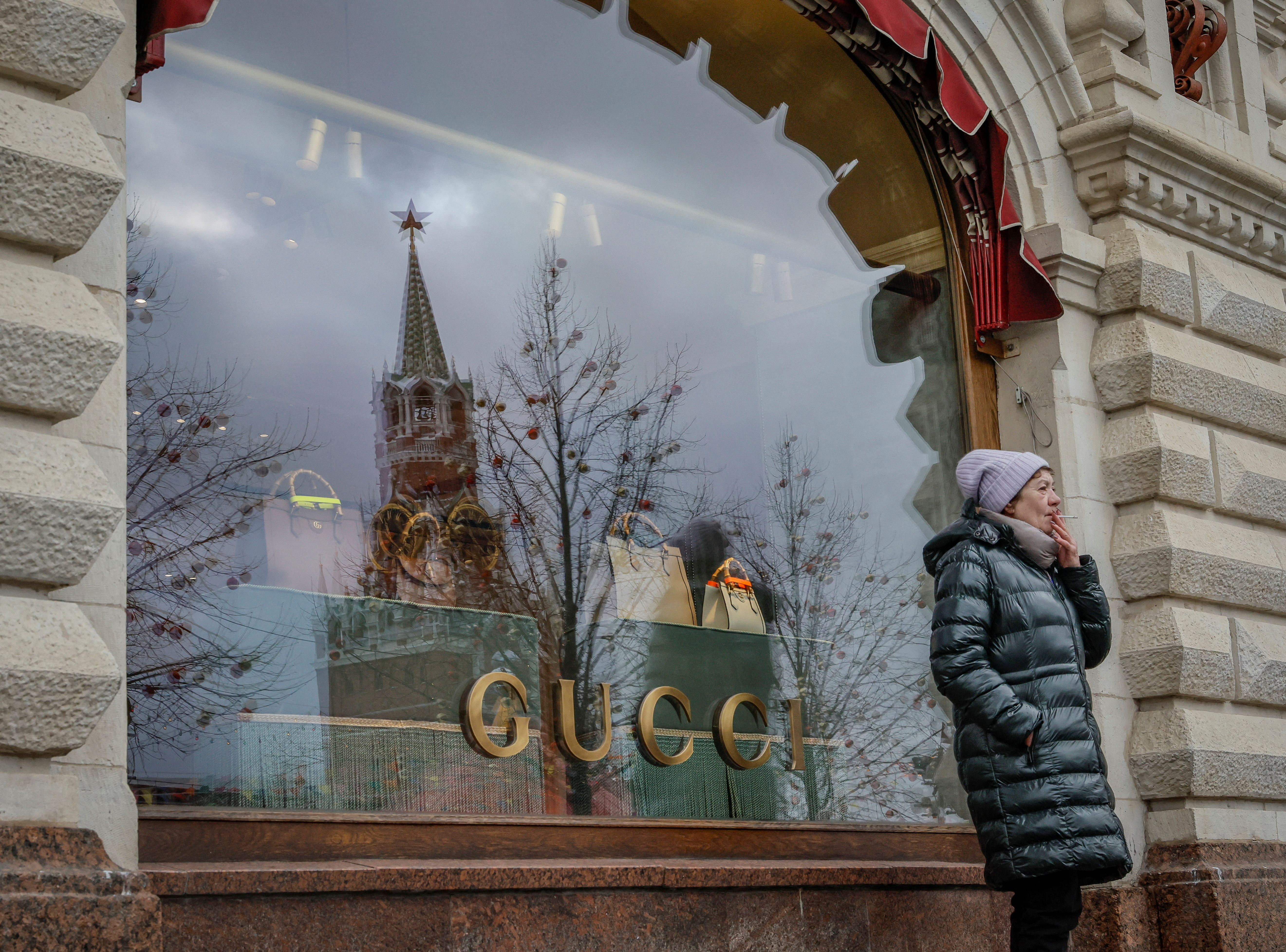 A woman smokes in front of a closed Gucci store in Moscow