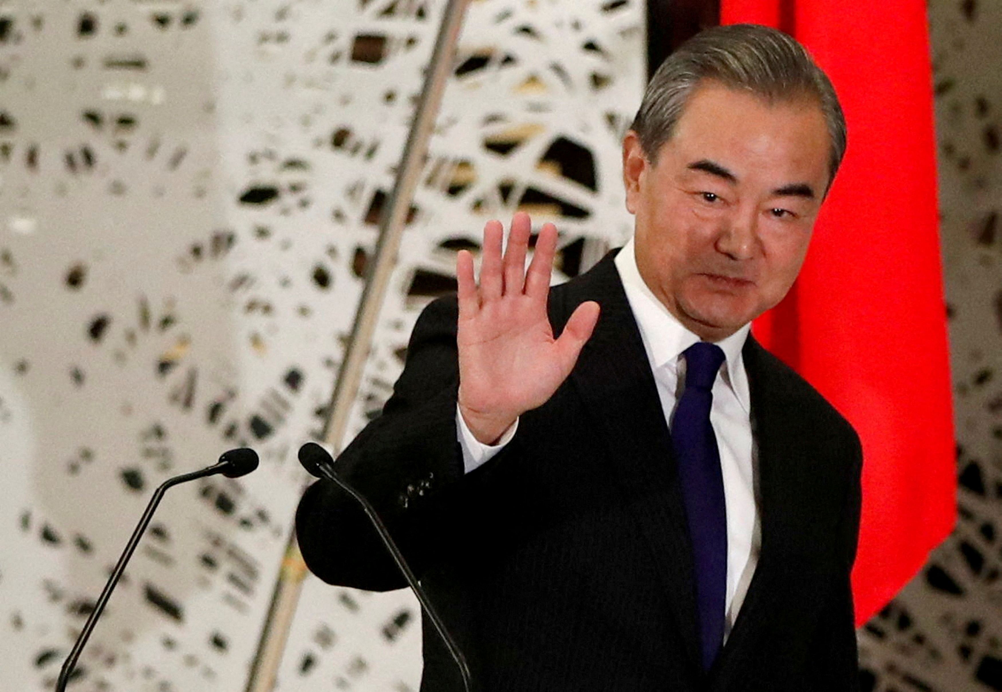 China's Wang Yi, state councillor and foreign minister, waves as he leaves a news conference in Tokyo