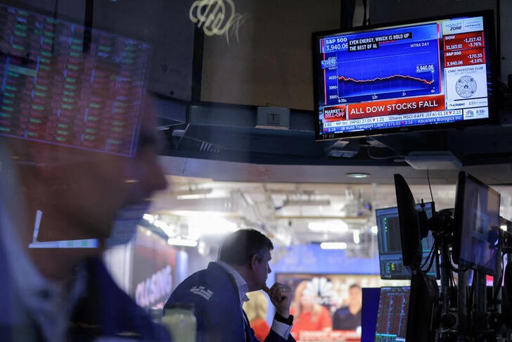 A screen displays market news as traders work on the trading floor at the New York Stock Exchange (NYSE) in Manhattan, New York City