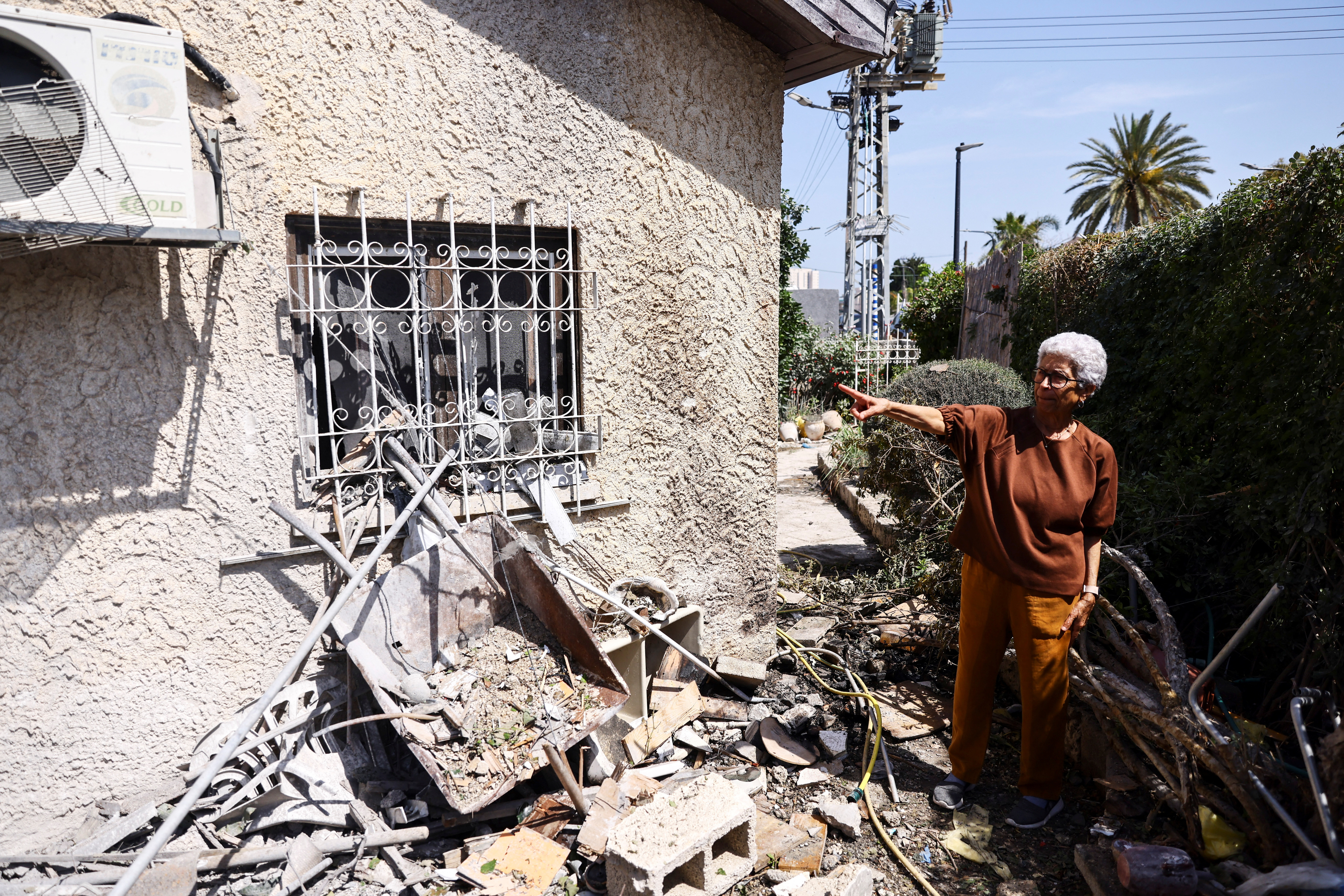 Miriam Karen gestures towards her damaged house which was hit by a rocket from Gaza for the second time in five years, in Ashkelon, southern Israel