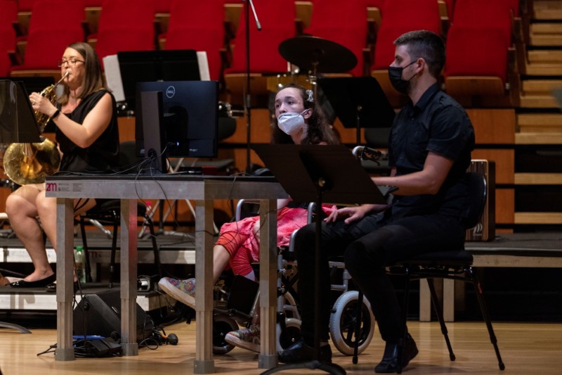 Alexandra Kerlidou, 21, who suffers from cerebral palsy, plays the "Eyeharp", a gaze-controlled digital software that allows people with disabilities to play music, next to computer scientist Zacharias Vamvakousis, during a concert in Athens, Greece, June 14, 2021. Picture taken June 14, 2021. REUTERS/Alkis Konstantinidis