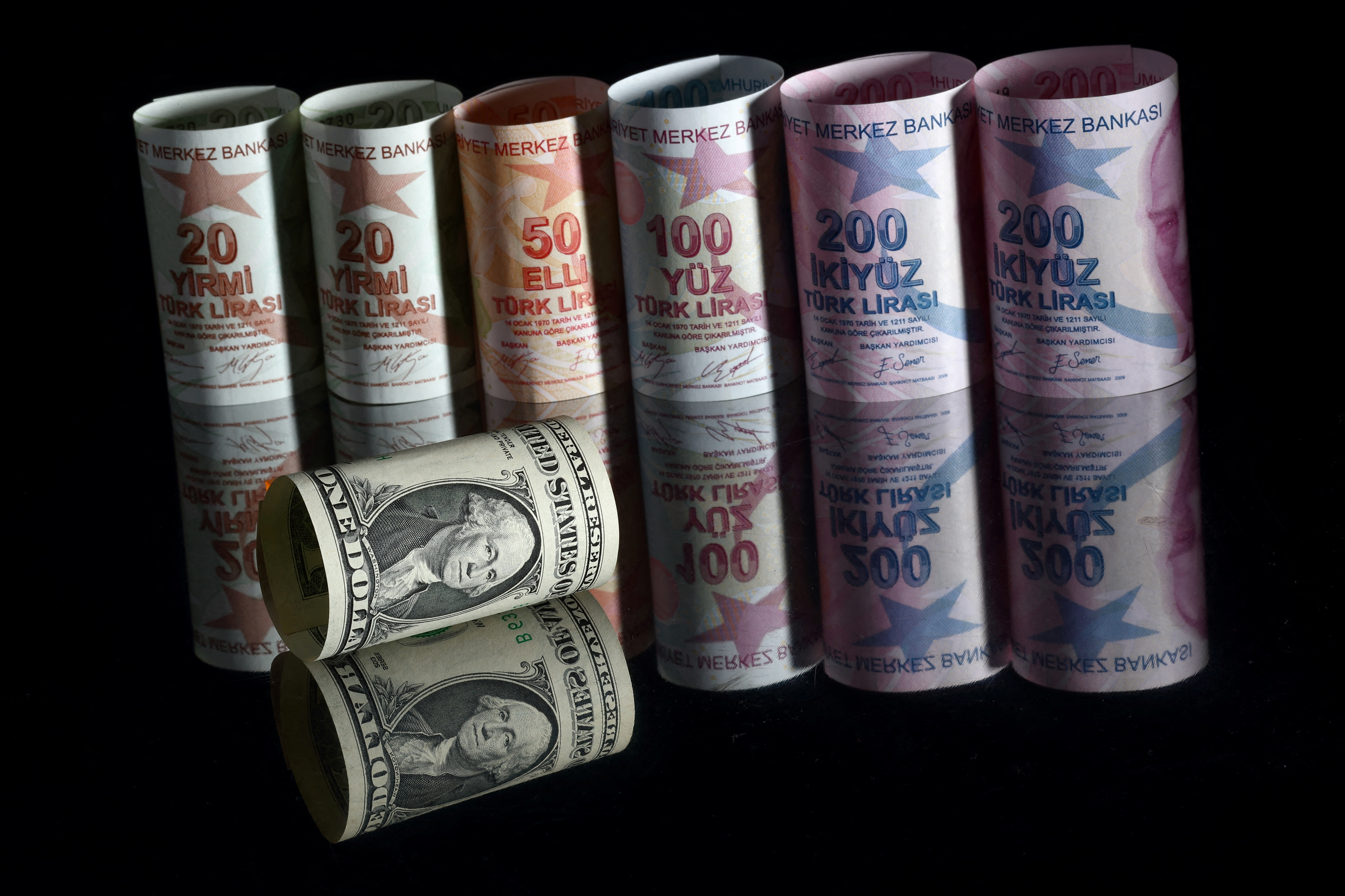A U.S. one dollar banknote is seen next to Turkish lira banknotes in this picture illustration