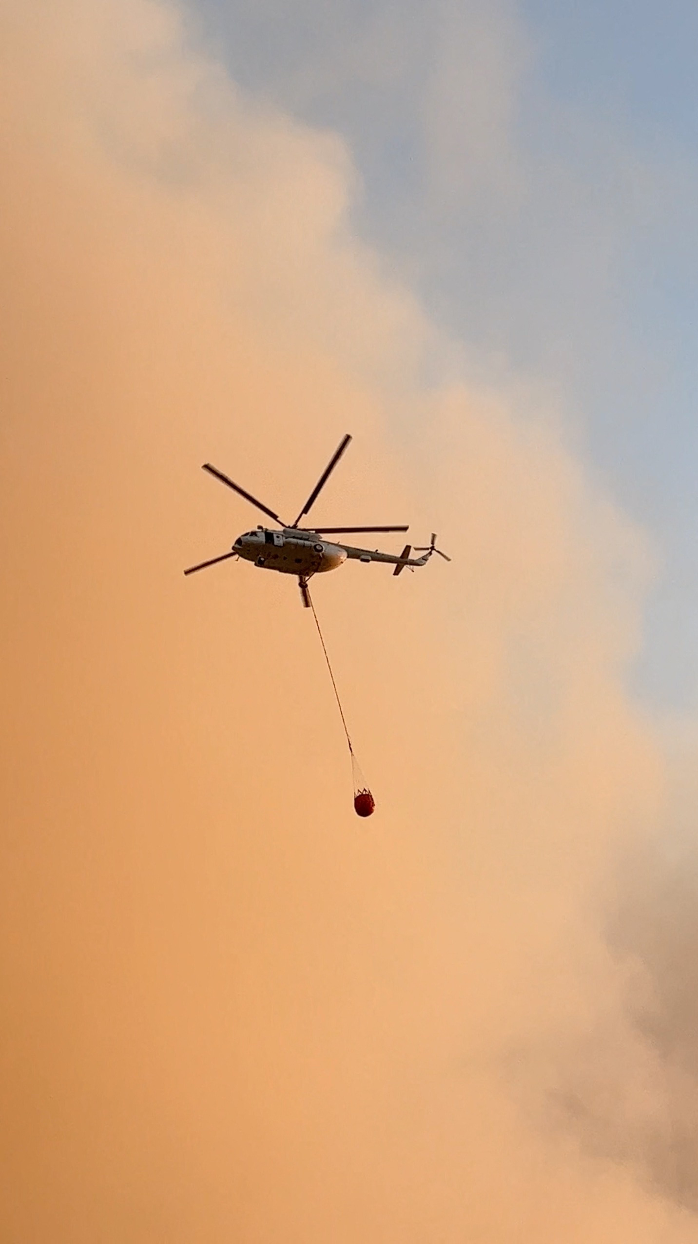 A firefighting helicopter flies as smoke billows from a wildfire, in Canakkale