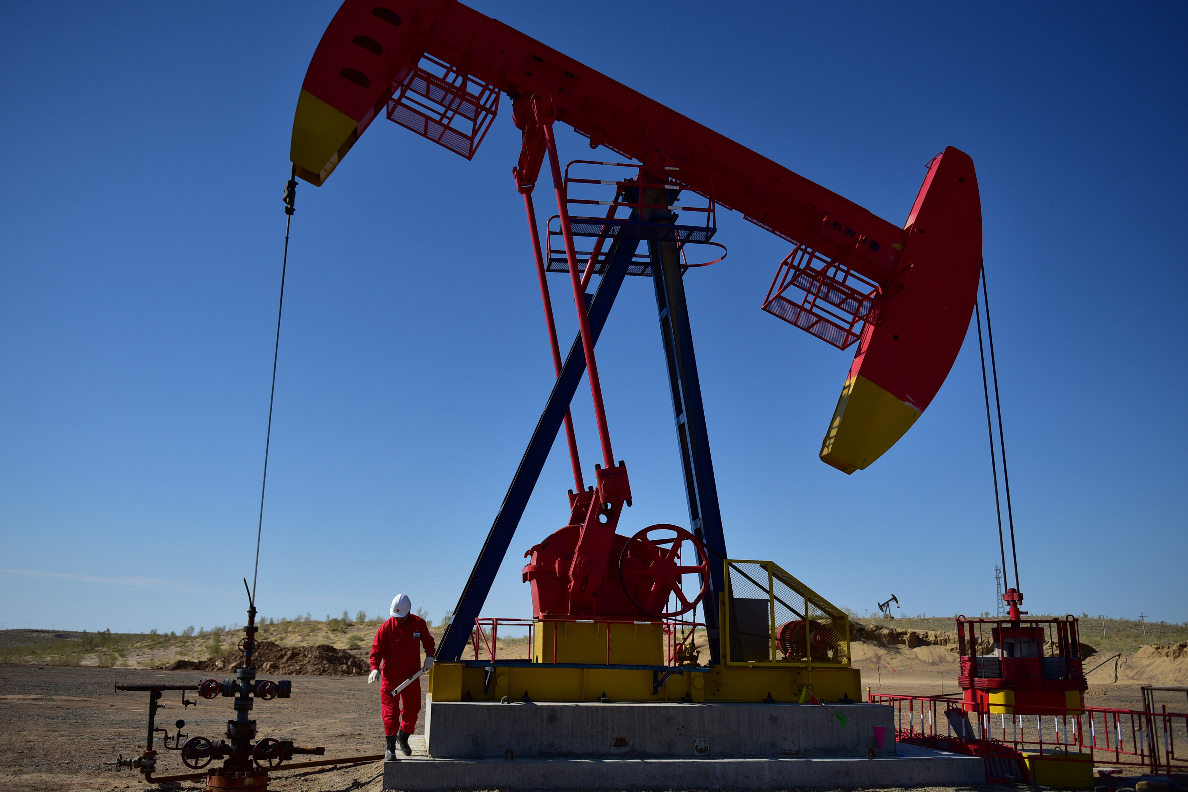 FILE PHOTO - Worker inspects a pump jack at an oil field in Tacheng, Xinjiang