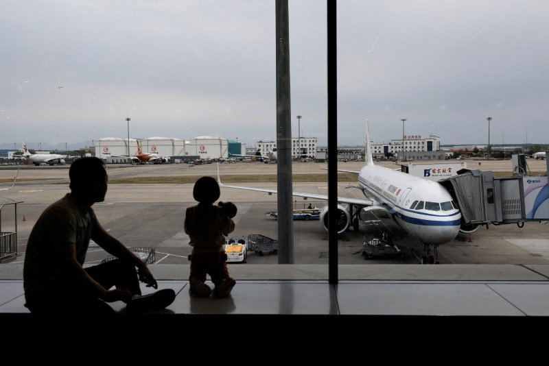 Passengers look at the tarmac as they wait for their flights at the Beijing Capital International Airport, in Beijing