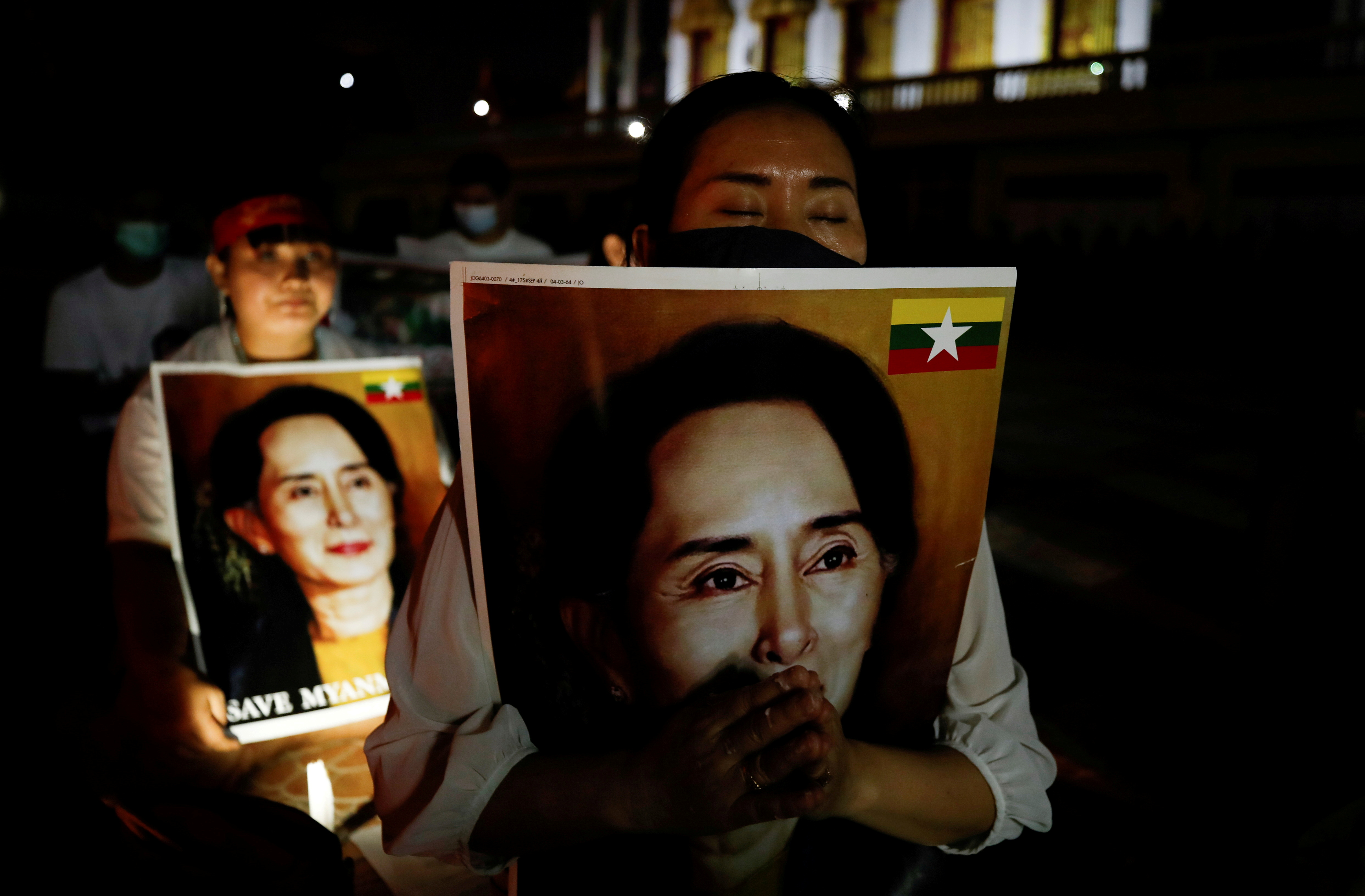 Migrants protesting against the military junta in Myanmar hold pictures of leader Aung San Suu Kyi, during a candlelight vigil at a Buddhist temple in Bangkok, Thailand, March 28, 2021. REUTERS/Jorge Silva/File Photo