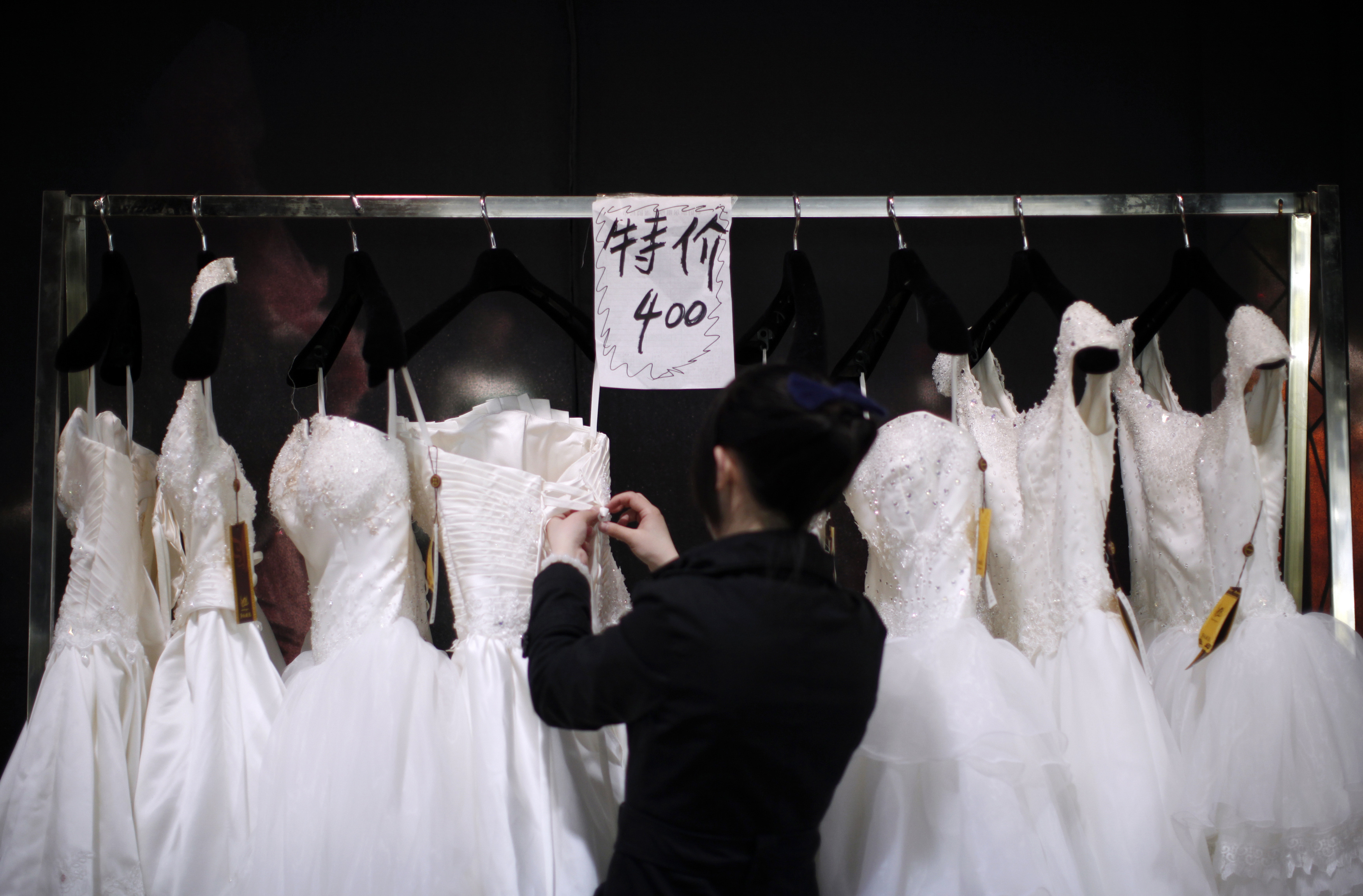 Vendor prepares wedding dresses at a show room during the China International Wedding Expo in Shanghai