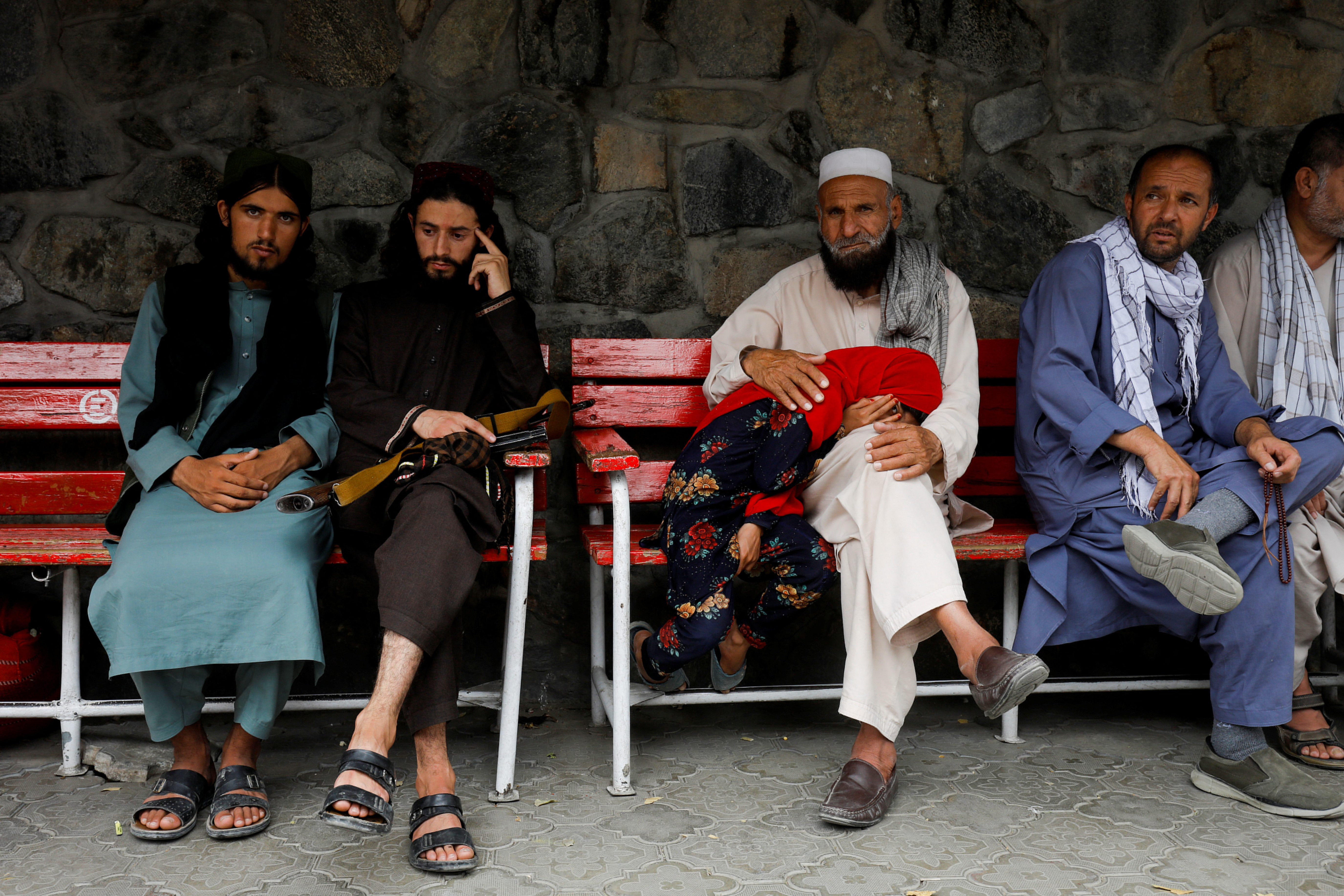 Family members of victims of last night's explosion sit as they wait in front of an emergency hospital in Kabul