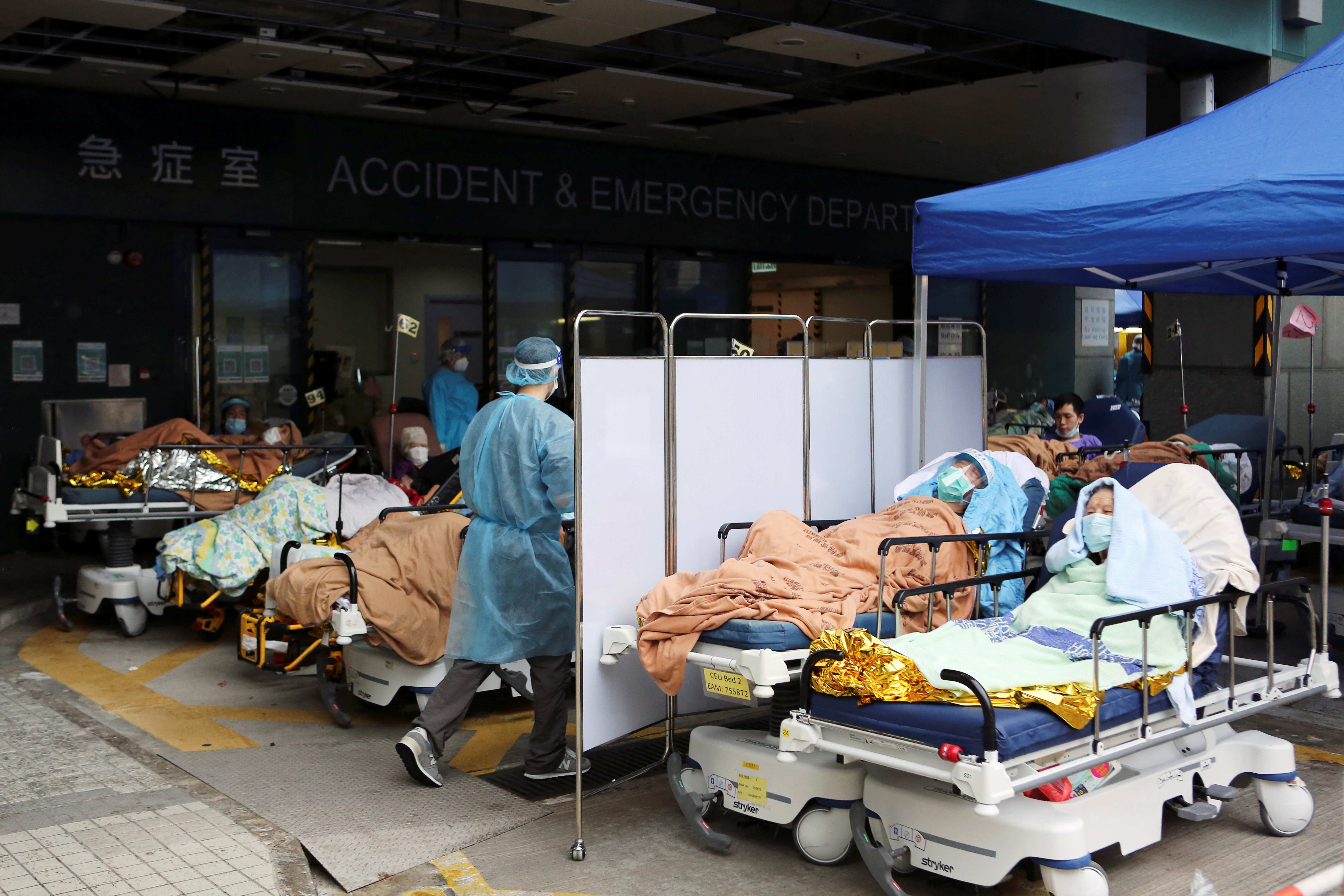 Medical worker Trevor Chung, 29, attends to patients, including 98-year-old Lam Foon, outside the accident and emergency ward of in Sham Shui Po district, following the coronavirus disease (COVID-19) outbreak in Hong Kong, China, February 17, 2022. Picture taken February 17, 2022. REUTERS/James Pomfret
