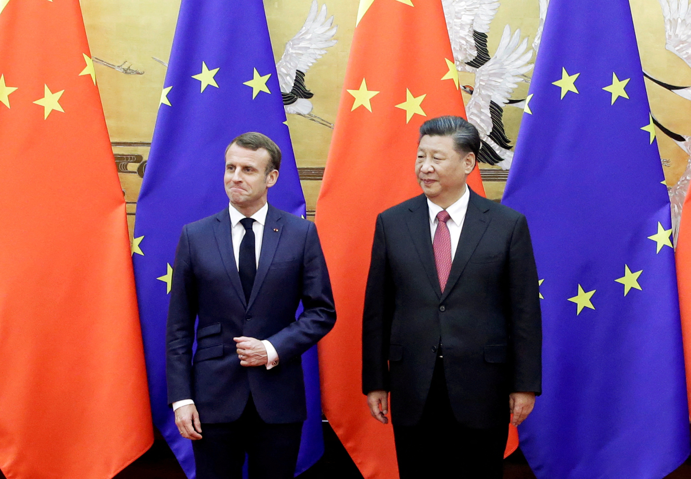 Chinese President Xi Jinping and French President Emmanuel Macron stand in front of Chinese and EU flags at a signing ceremony inside the Great Hall of the People in Beijing