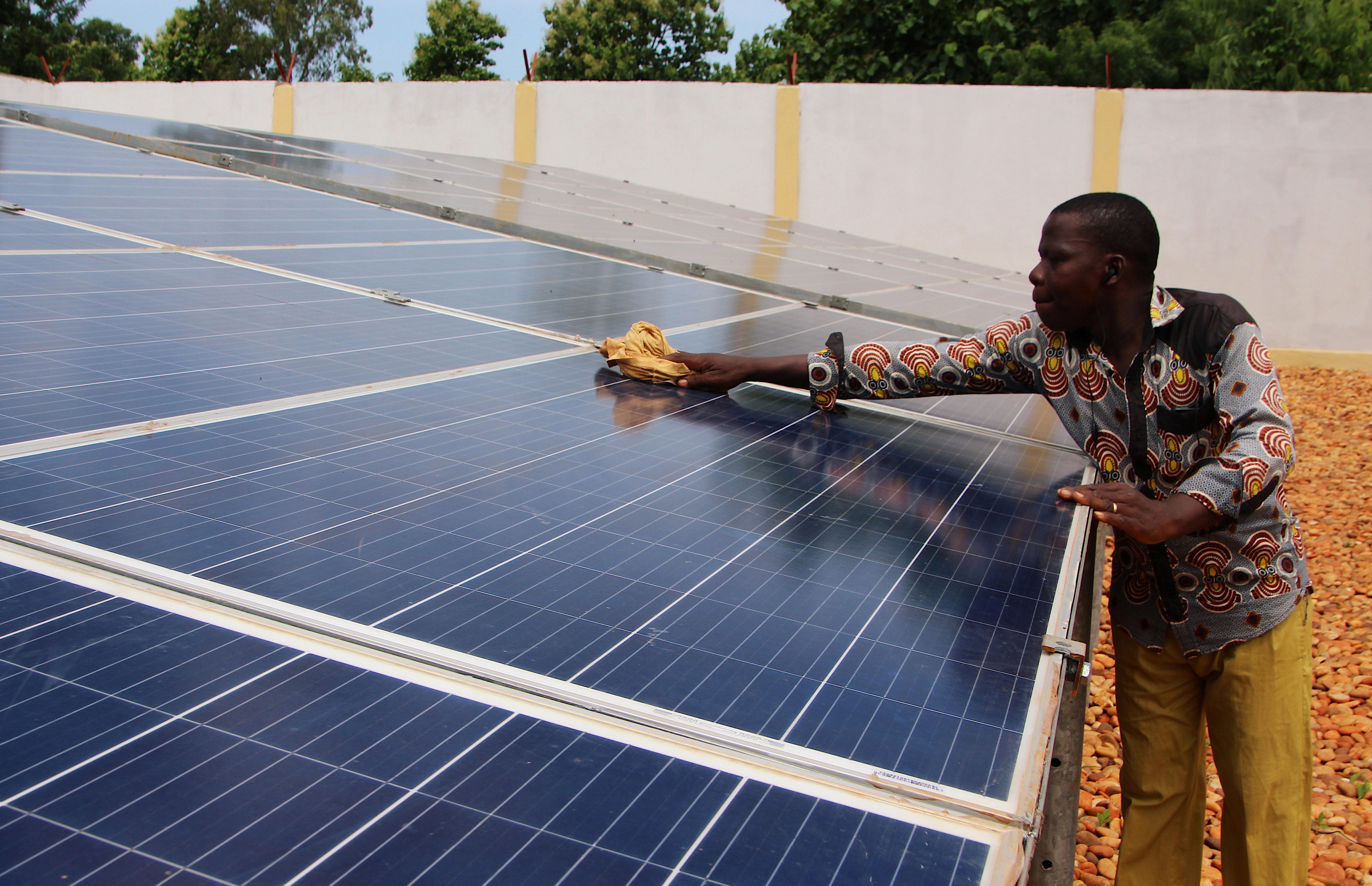 A technician cleans solar panels in Togo. Many renewable projects in developing countries have failed because funding failed to plan for operation and maintenance needs. REUTERS/Noel Kokou Tadegnon