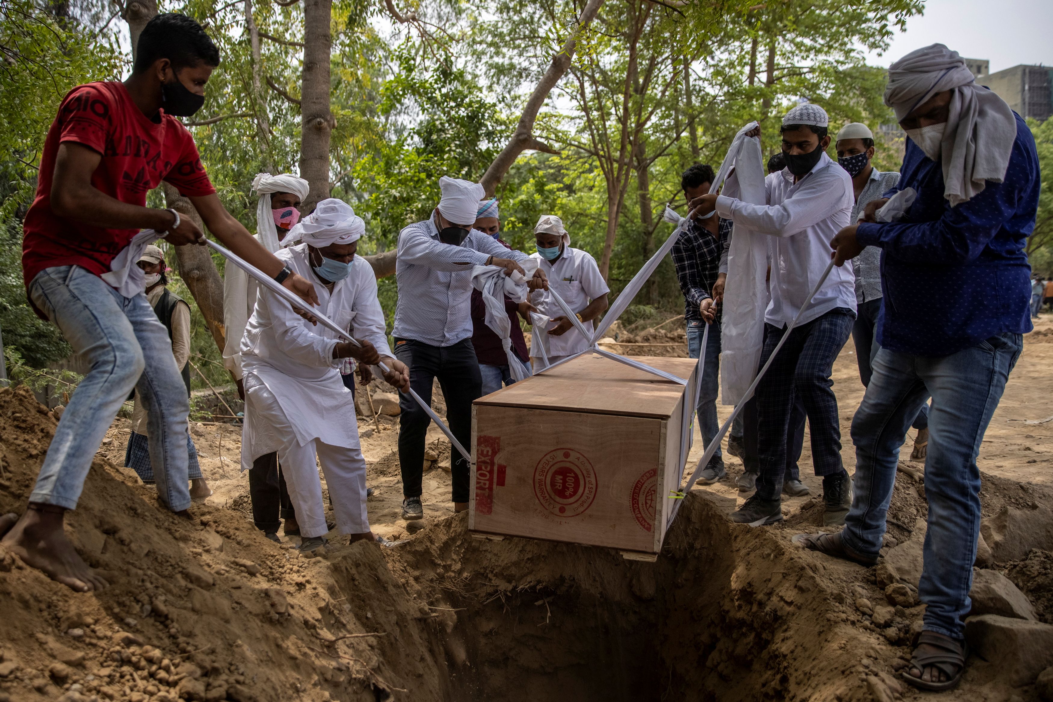 People bury the body of a man at a graveyard in New Delhi