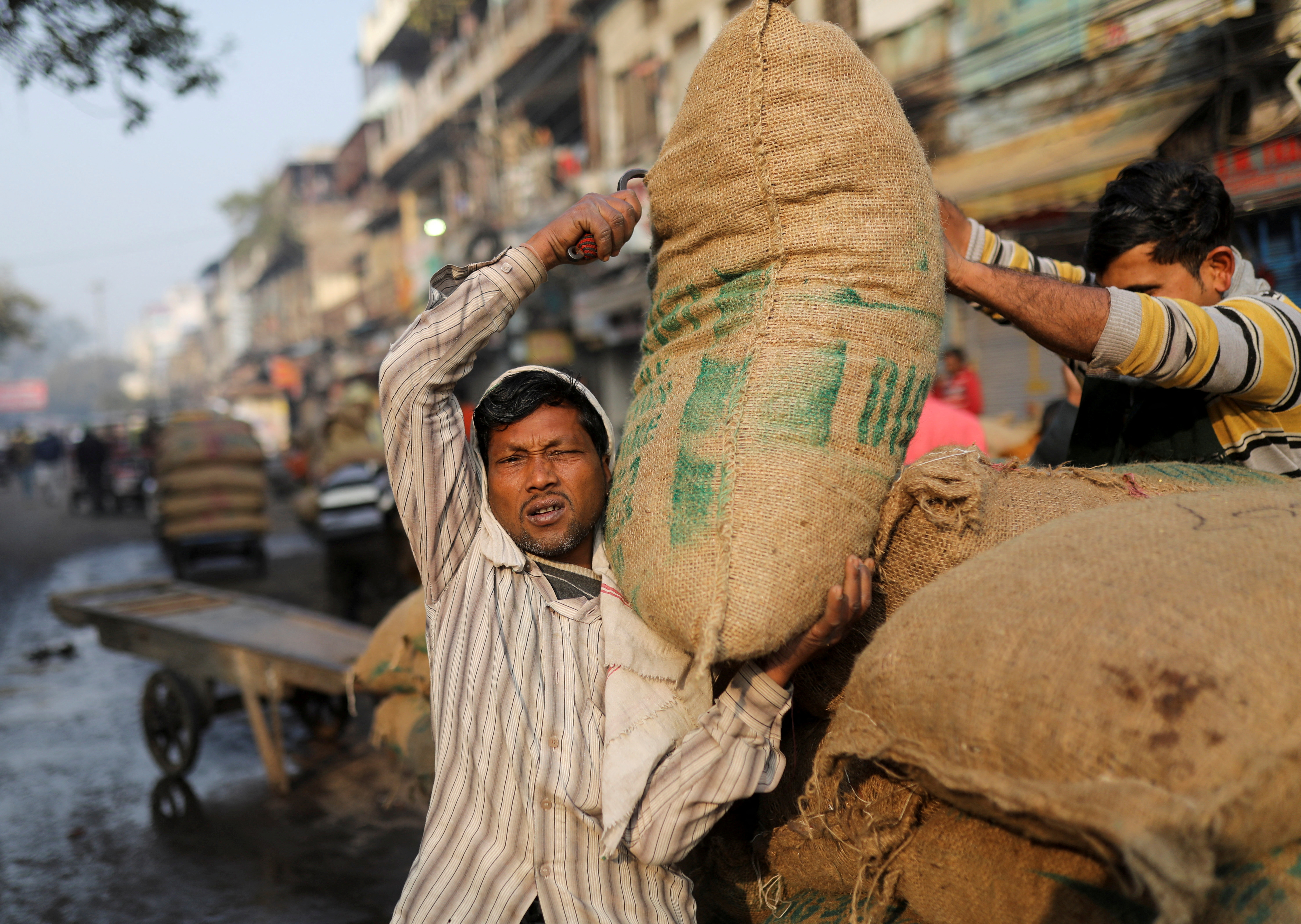 A labourer reacts as he carries a sack at a wholesale market in the old quarters of Delhi