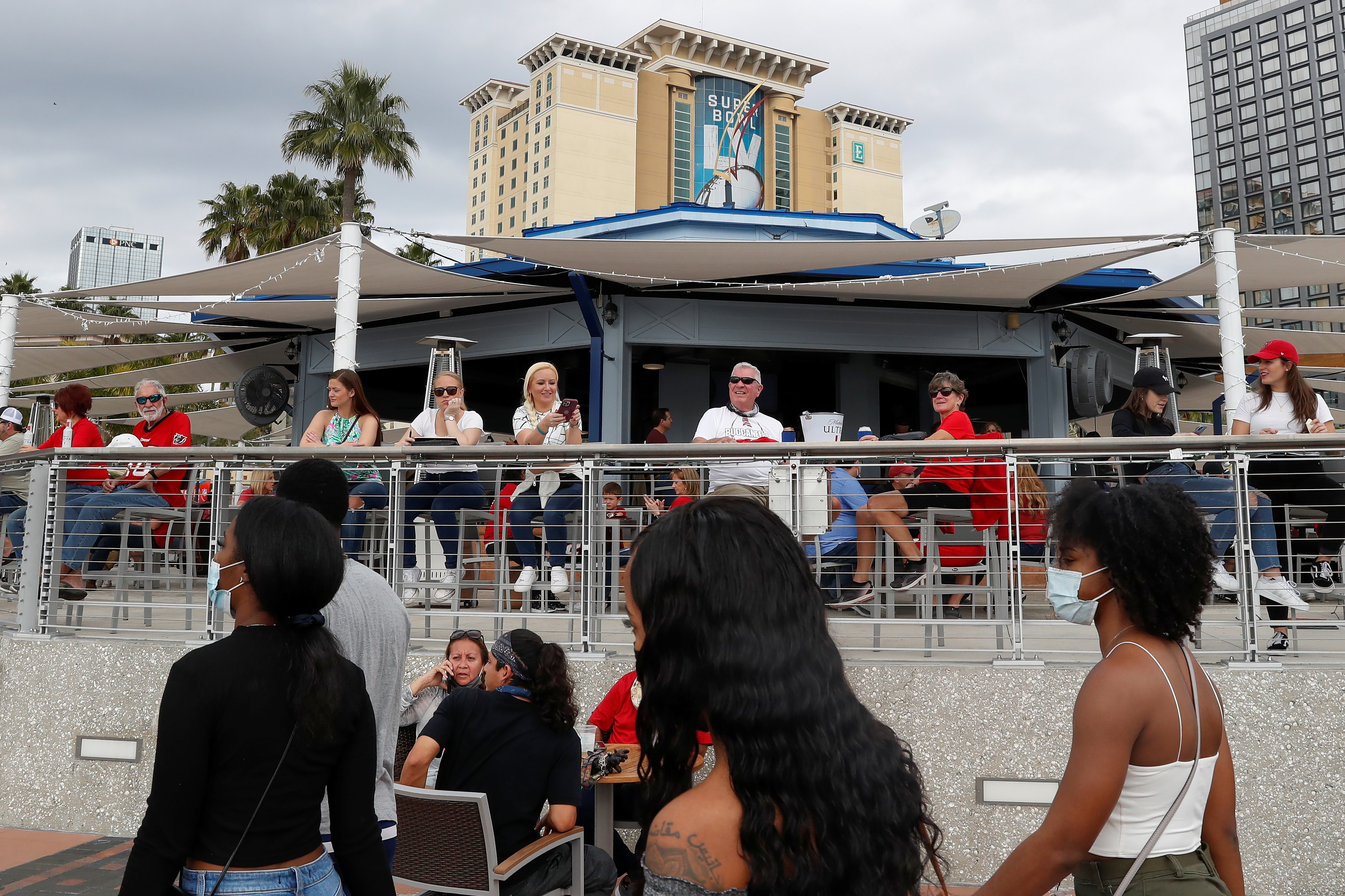 People sit at an outdoor terrace outside the Tampa Convention Center a day before the Super Bowl LV between the Kansas City Chiefs and Tampa Bay Buccaneers, as the spread of the coronavirus disease (COVID-19) continues in Tampa, Florida, February 6, 2021. REUTERS/Shannon Stapleton