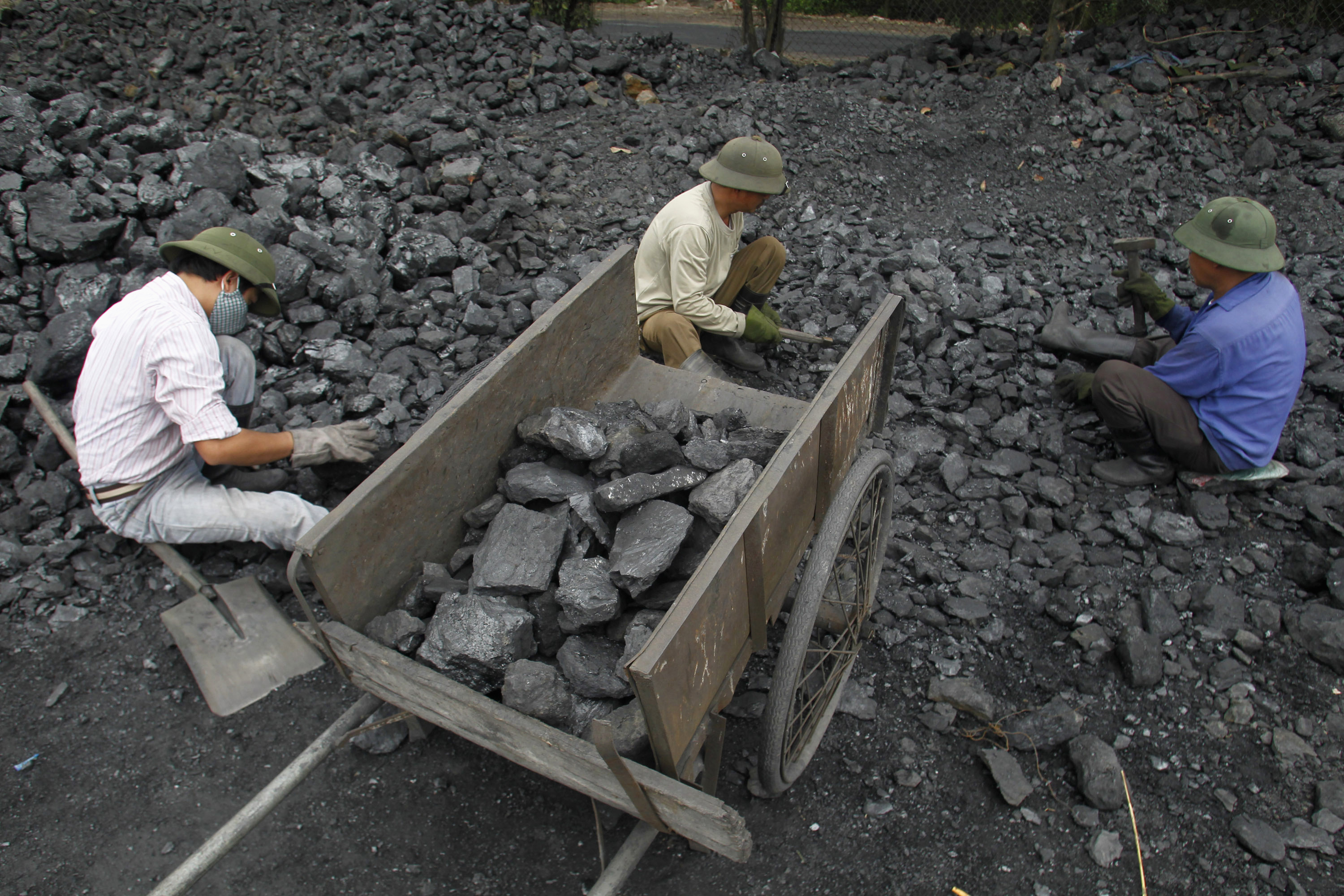 Workers pick out gravel from coal at a coal port in Hanoi