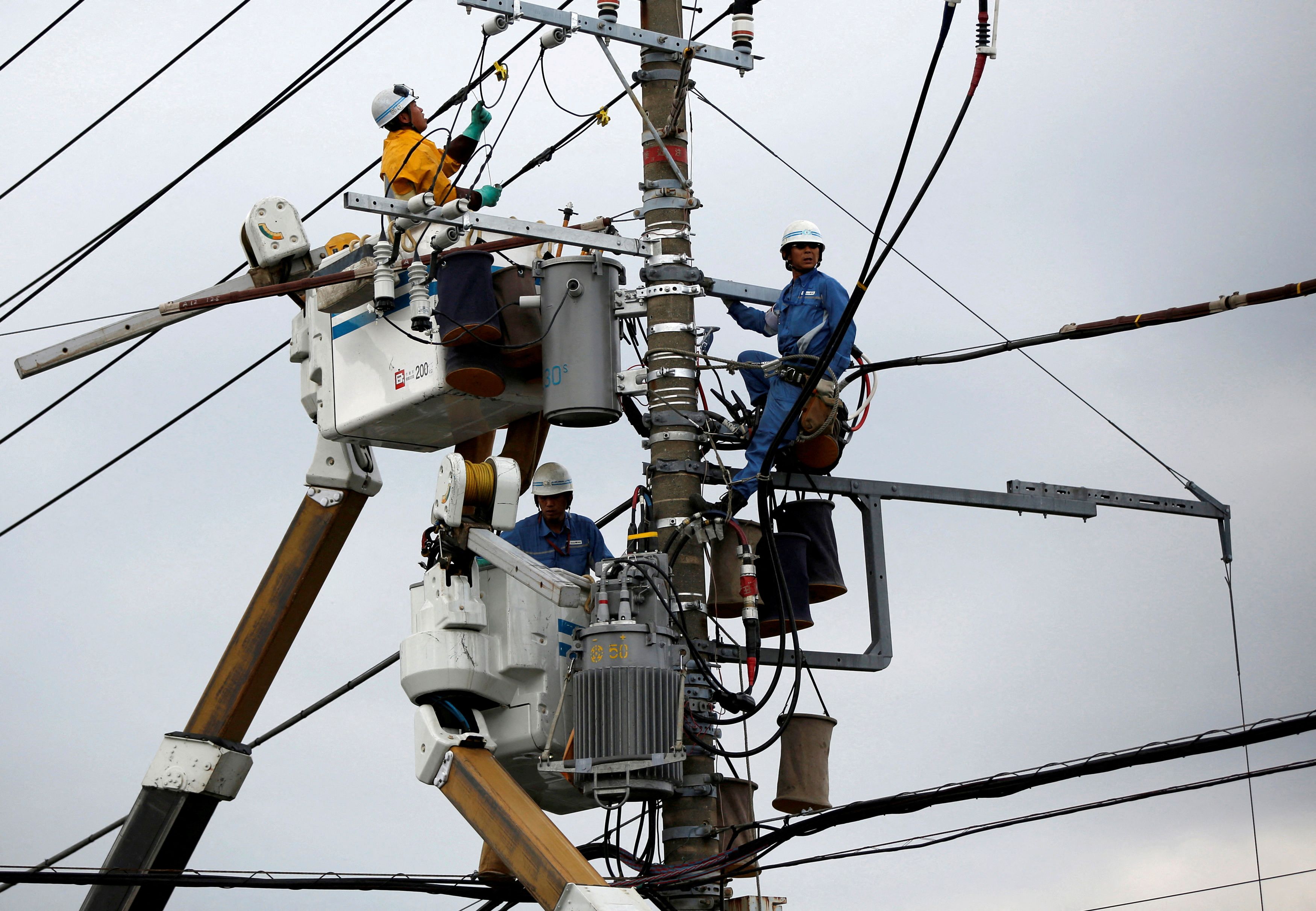 Men work around an electric utility pole along the street in Urayasu