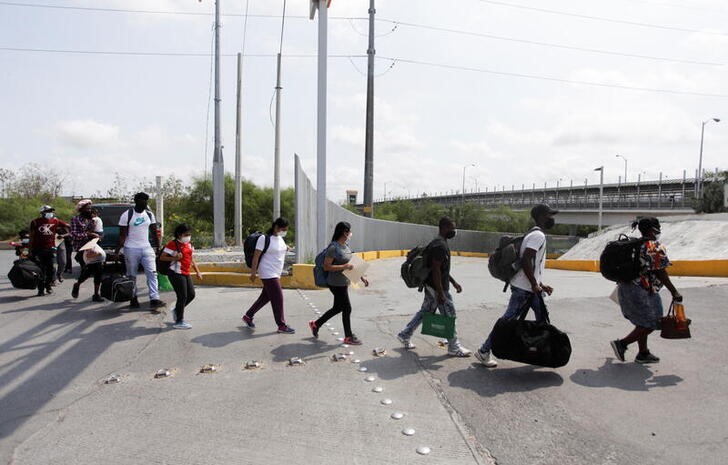 Migrants walk across the Reynosa-Hidalgo International Border Bridge after being accepted by the U.S. government with legal assistance, in Reynosa