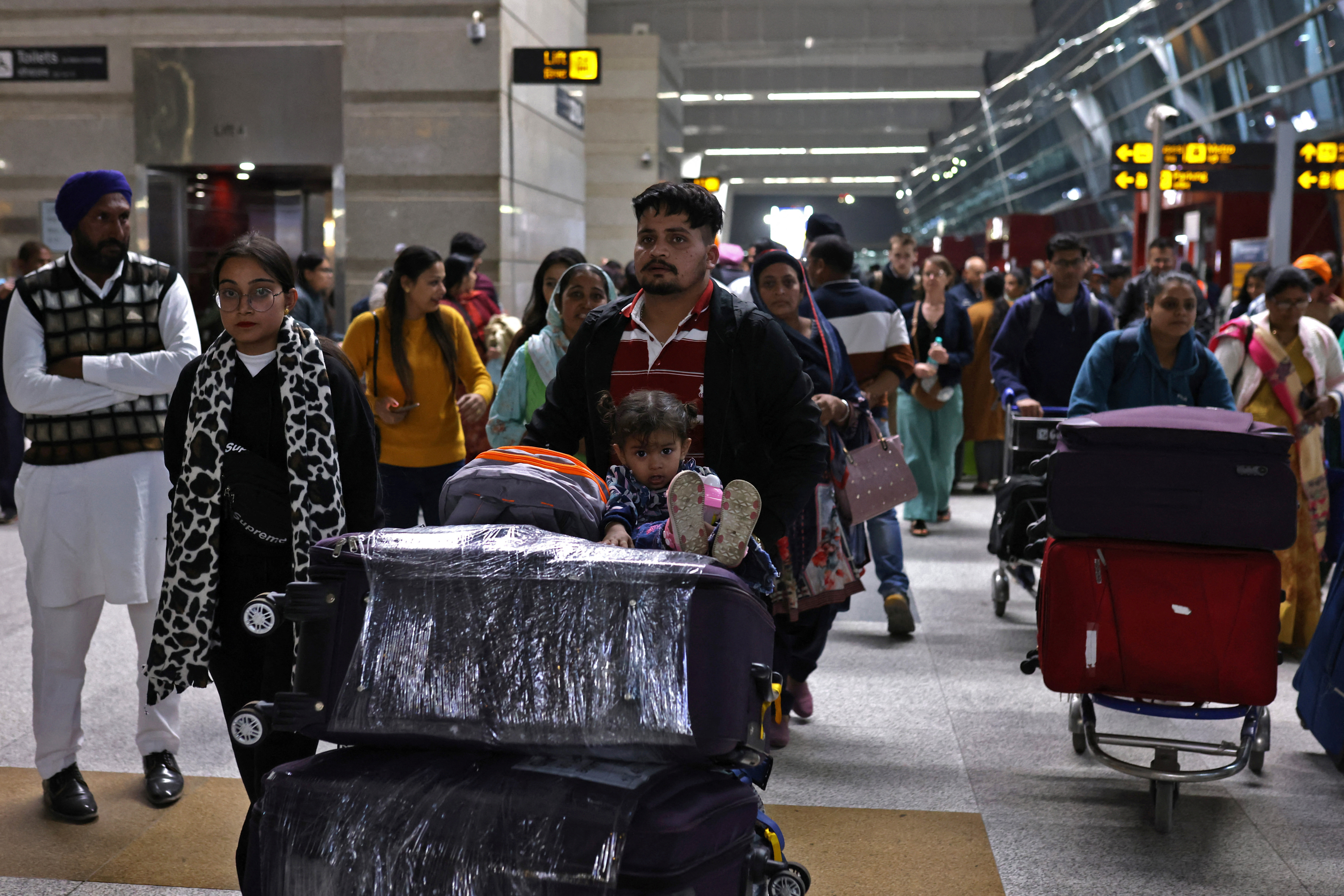 Travellers push trolleys with their luggage at the departure area of Indira Gandhi International Airport in New Delhi