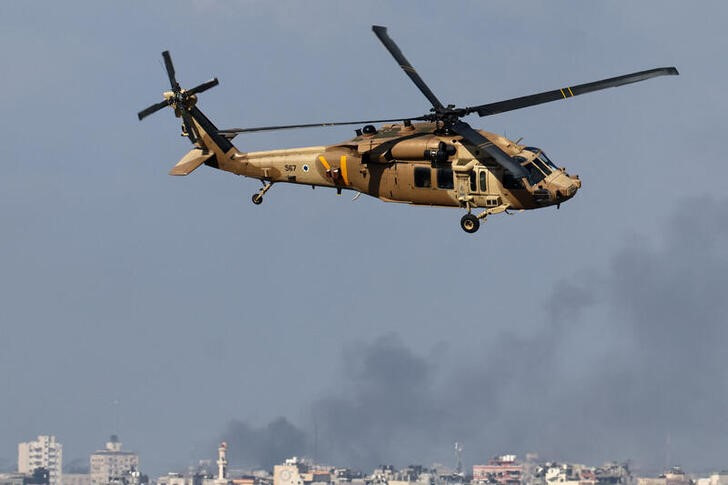 Israeli military helicopter flies as smoke rises over Gaza, as seen from southern Israel