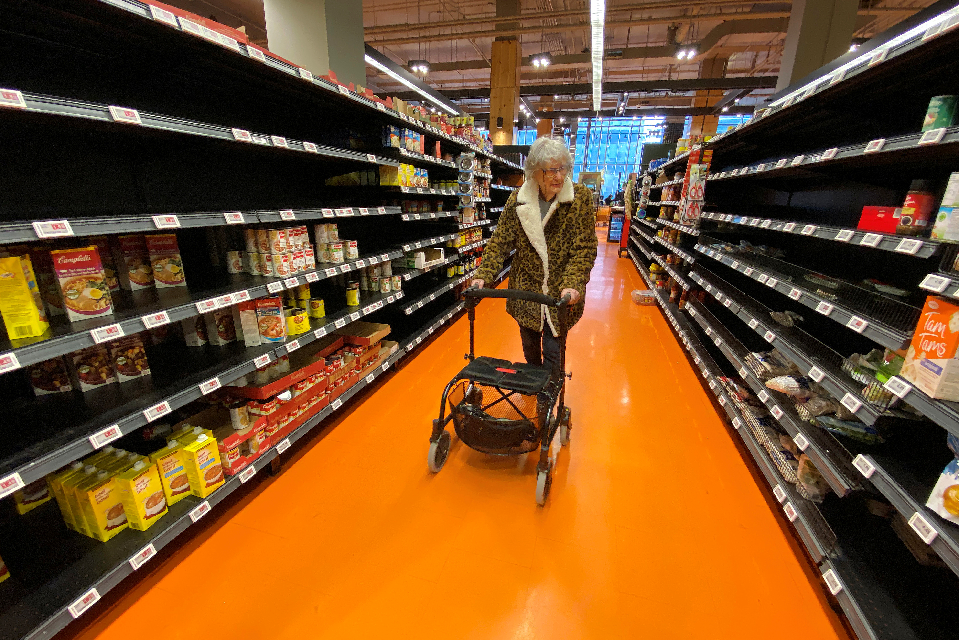 A shopper walks through an aisle empty of pasta, rice, beans and soup at a Loblaws supermarket in Toronto