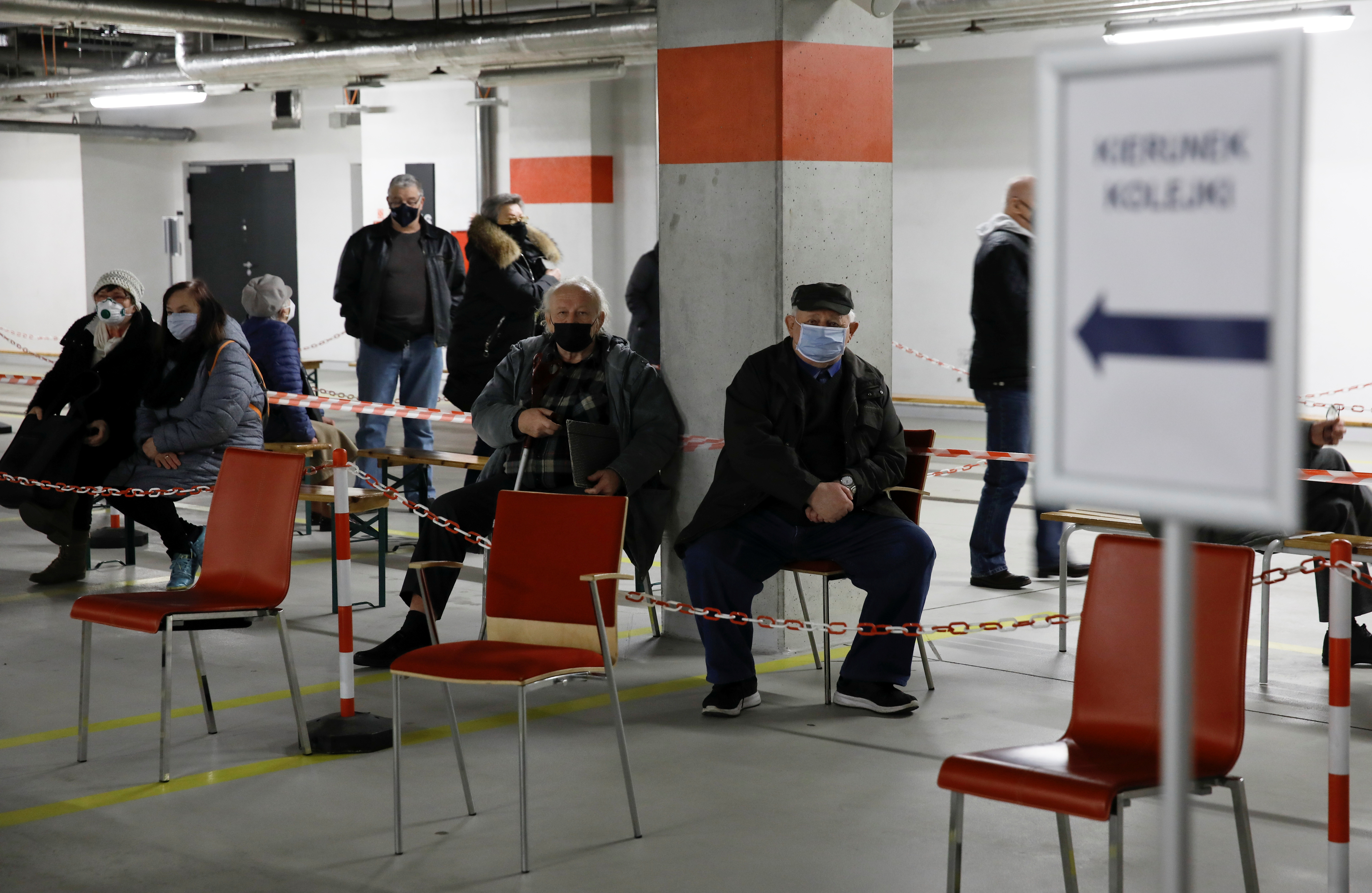 People wearing protective masks wait in line at the coronavirus disease (COVID-19) vaccine centre situated at a temporary hospital organised at the National Stadium in Warsaw