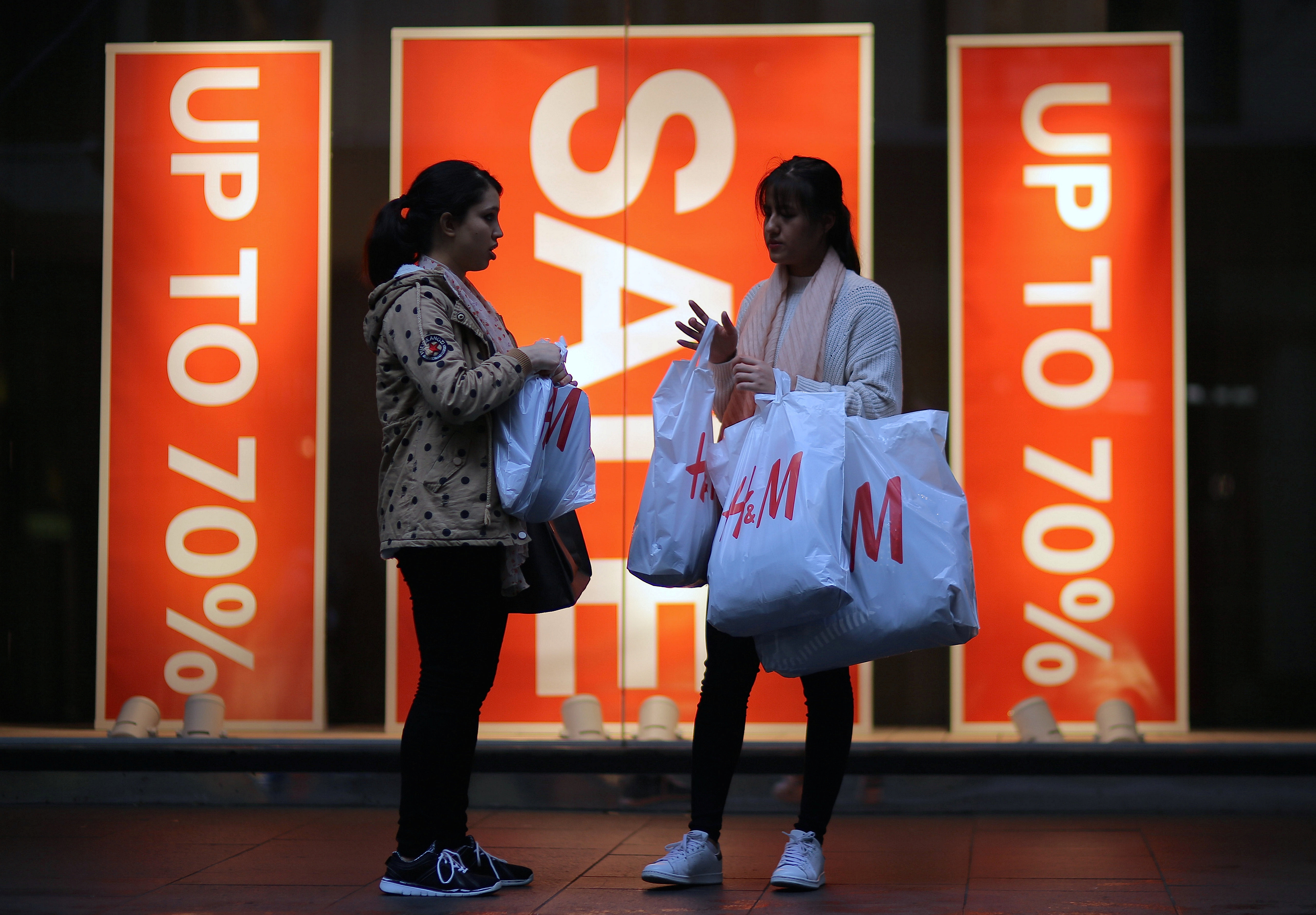 Shoppers carry shopping bags containing purchased goods outside a retail store displaying a sale sign in central Sydney, Australia, June 14, 2017. REUTERS/Steven Saphore